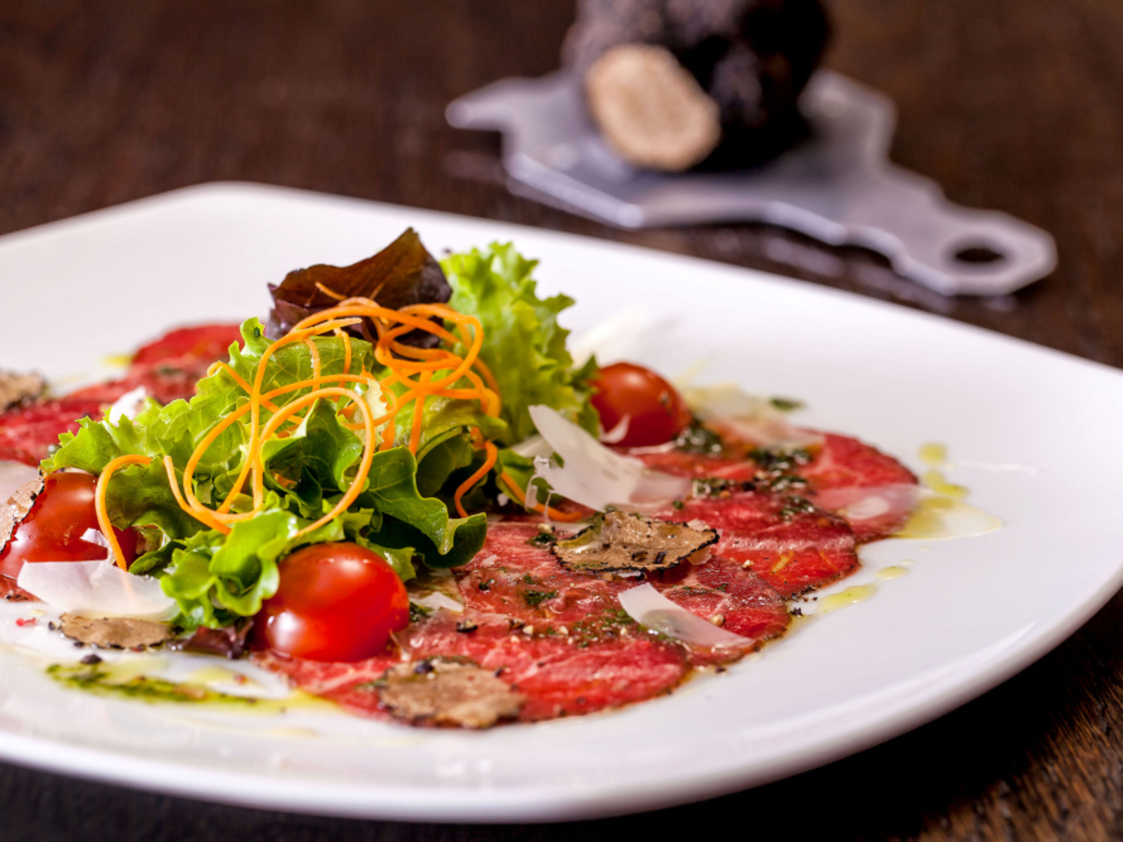 Beef carpaccio with truffle, cherry tomatoes and fresh salad on a white plate. Beef carpaccio with truffle, cherry tomatoes and fresh salad on a white plate.