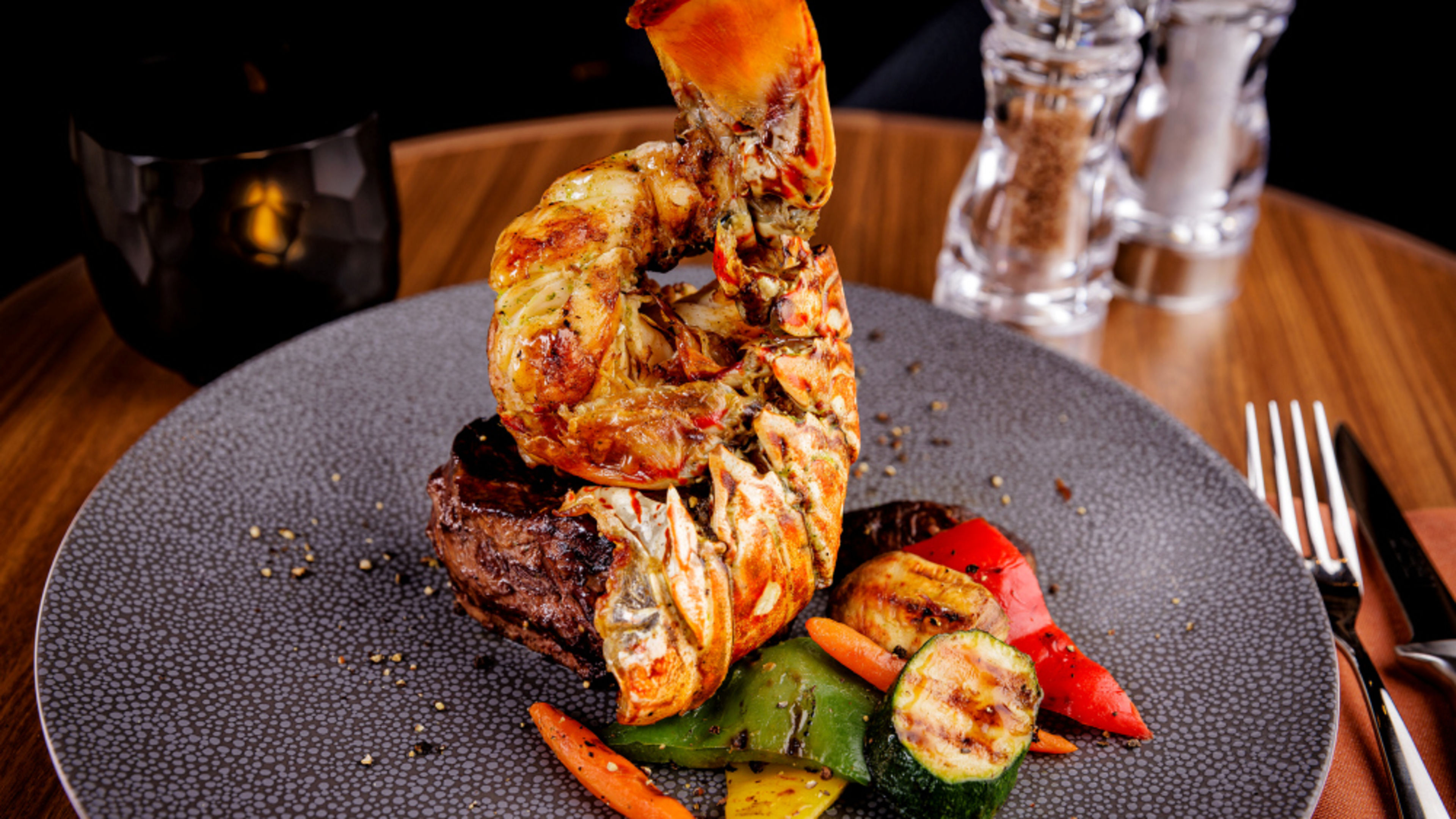 Lobster on steak with grilled vegetables on a grey plate. Lobster on steak with grilled vegetables on a grey plate.