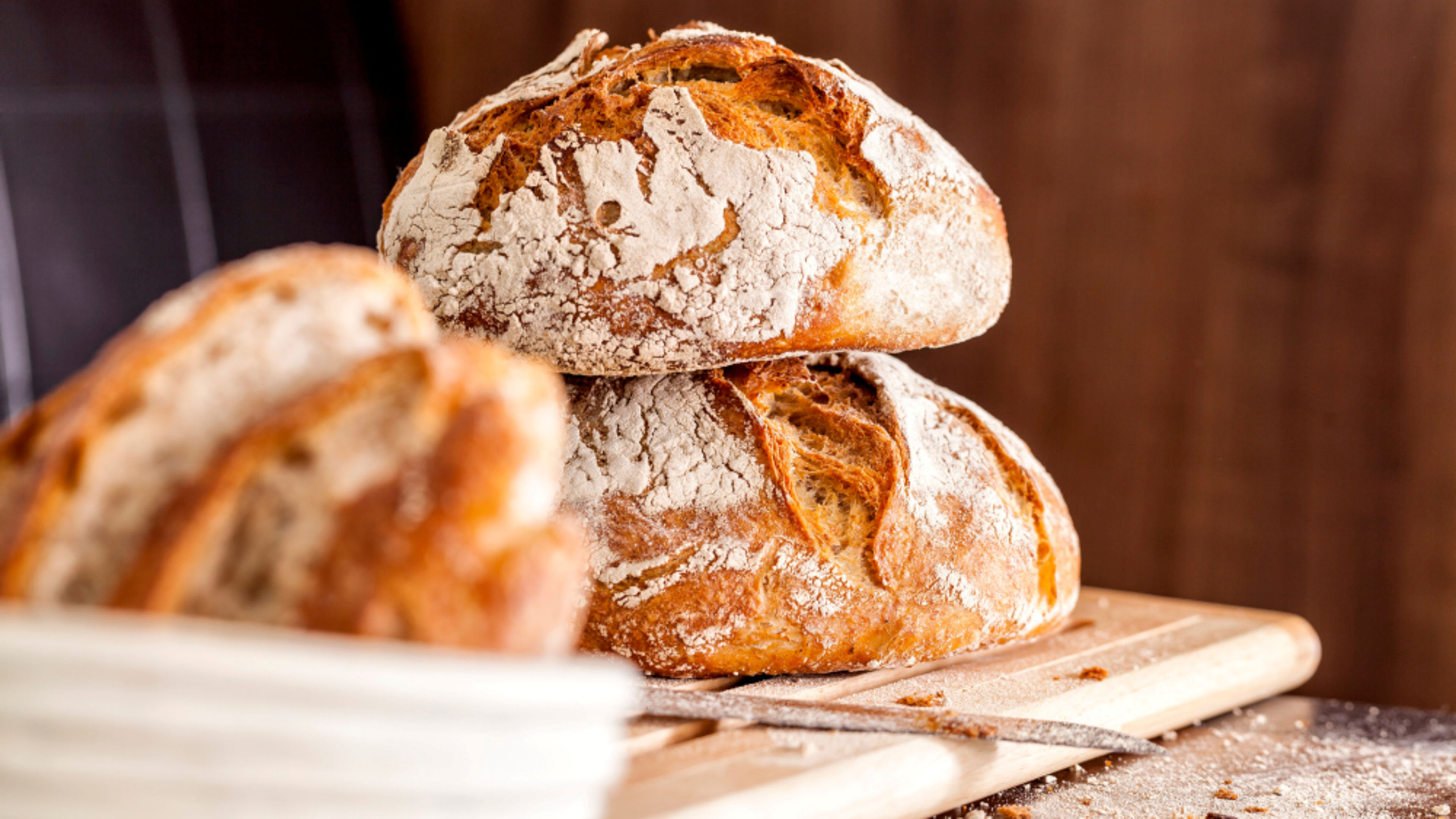 Two Artisan loaves of bread on a wooden board, dusted with flour. Two Artisan loaves of bread on a wooden board, dusted with flour.