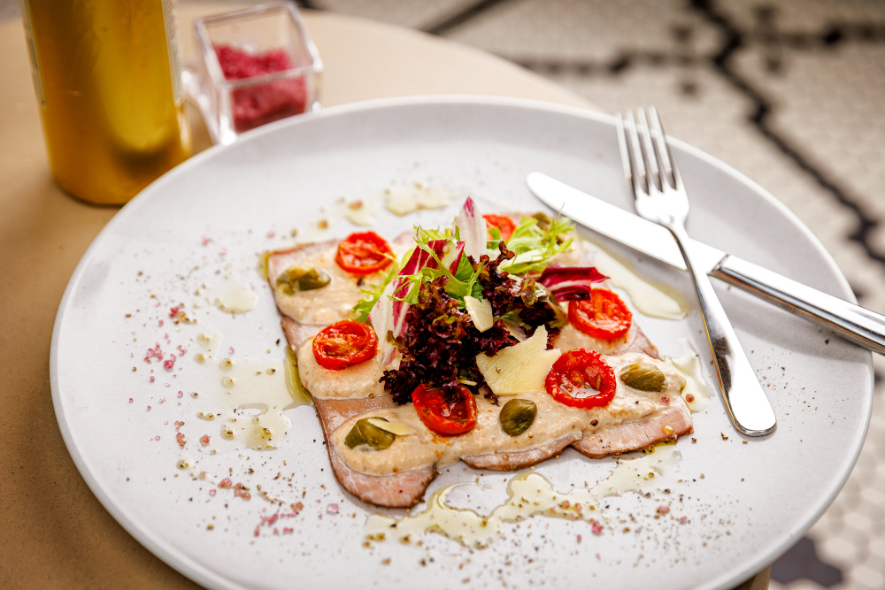 A plate of vitello tonnato, tomatoes, capers and salad.