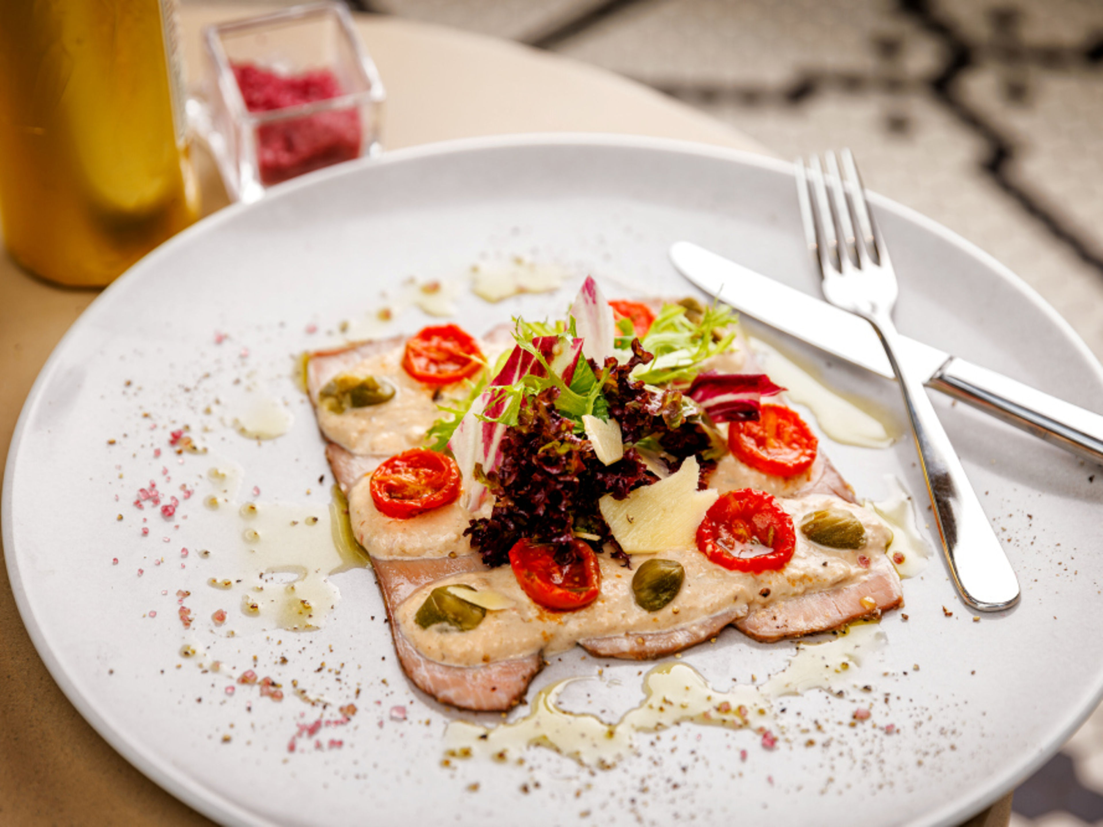 A plate of vitello tonnato, tomatoes, capers and salad. A plate of vitello tonnato, tomatoes, capers and salad.