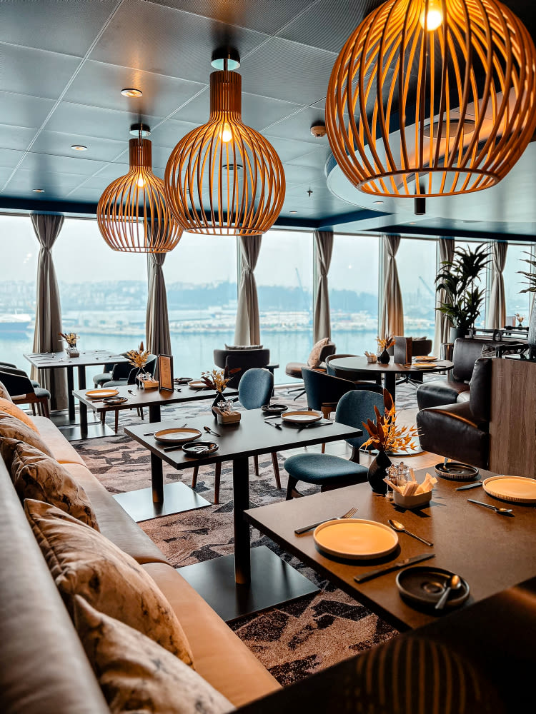 Restaurant Høfde with modern lamps, set tables, harbour view.