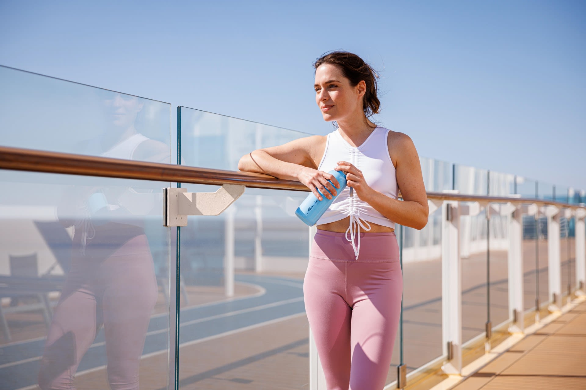 Frau in Sportkleidung mit Wasserflasche auf Kreuzfahrtschiff-Deck. Frau in Sportkleidung mit Wasserflasche auf Kreuzfahrtschiff-Deck.