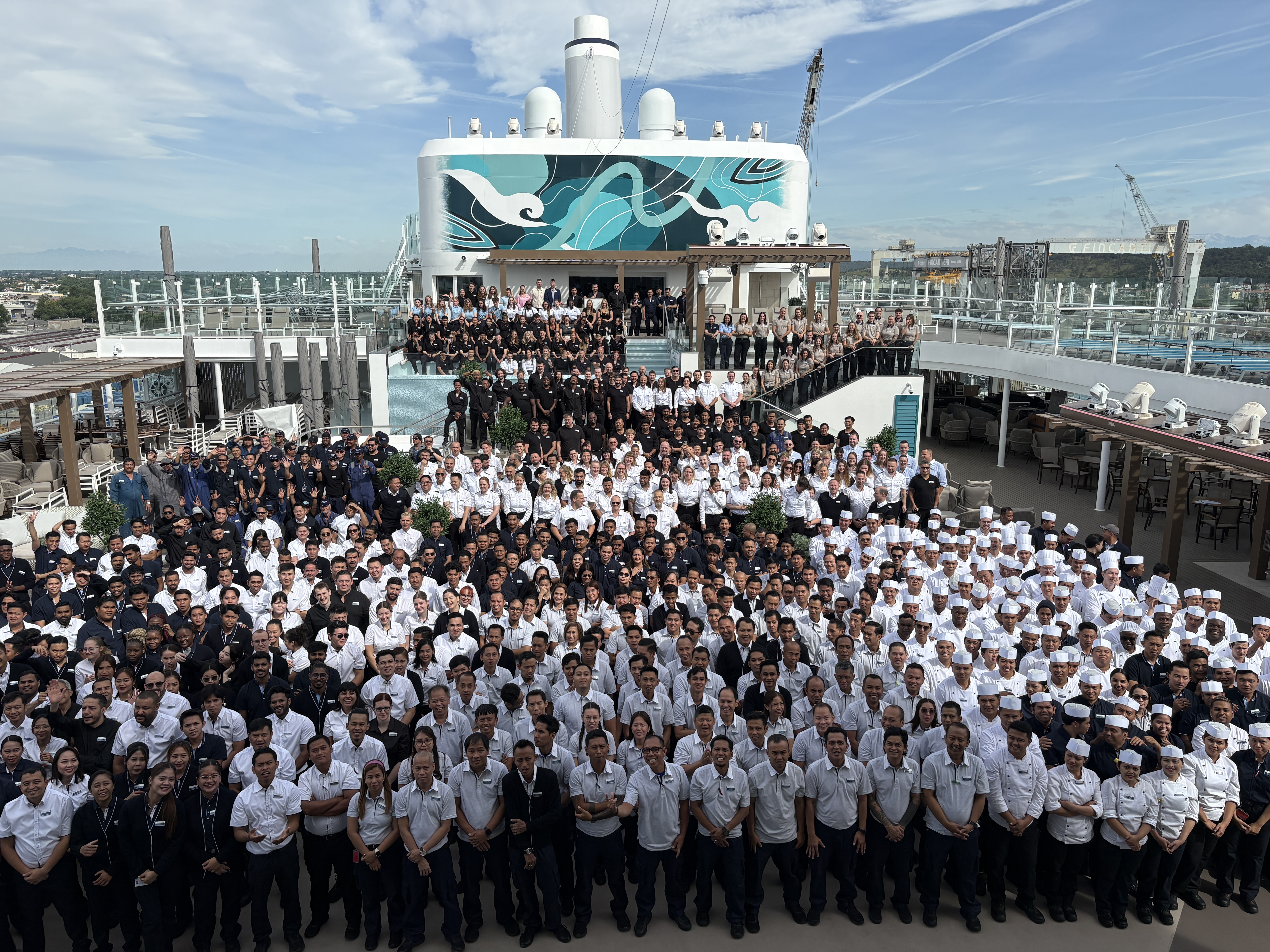 Große Crew-Gruppe posiert auf dem Deck eines Kreuzfahrtschiffs der Mein Schiff® Flotte.