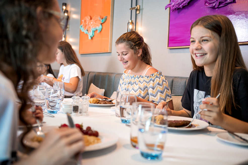 Girls are laughing and eating together in a restaurant.