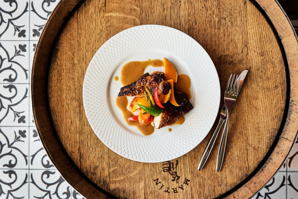 Le Coq auf Vin auf Holztisch, dekoriert mit Gemüse und Sauce.