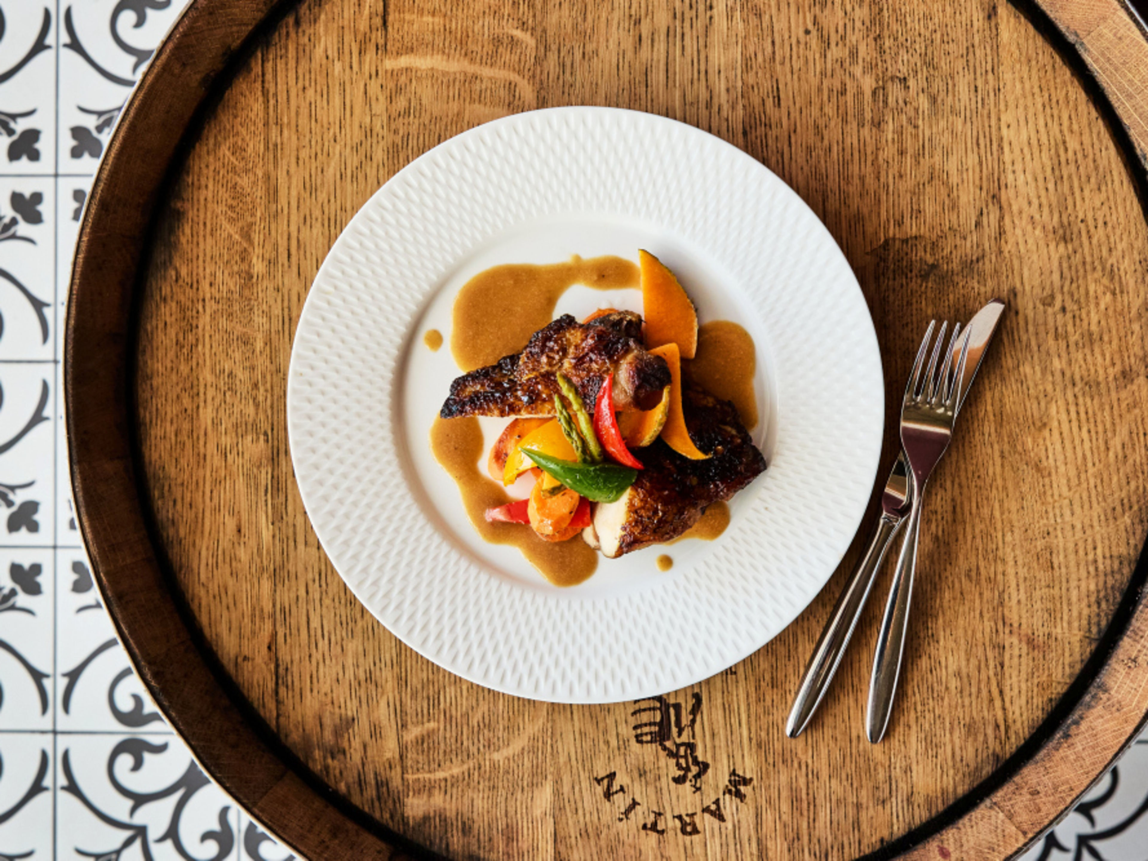 Le Coq auf Vin auf Holztisch, dekoriert mit Gemüse und Sauce. Le Coq auf Vin auf Holztisch, dekoriert mit Gemüse und Sauce.