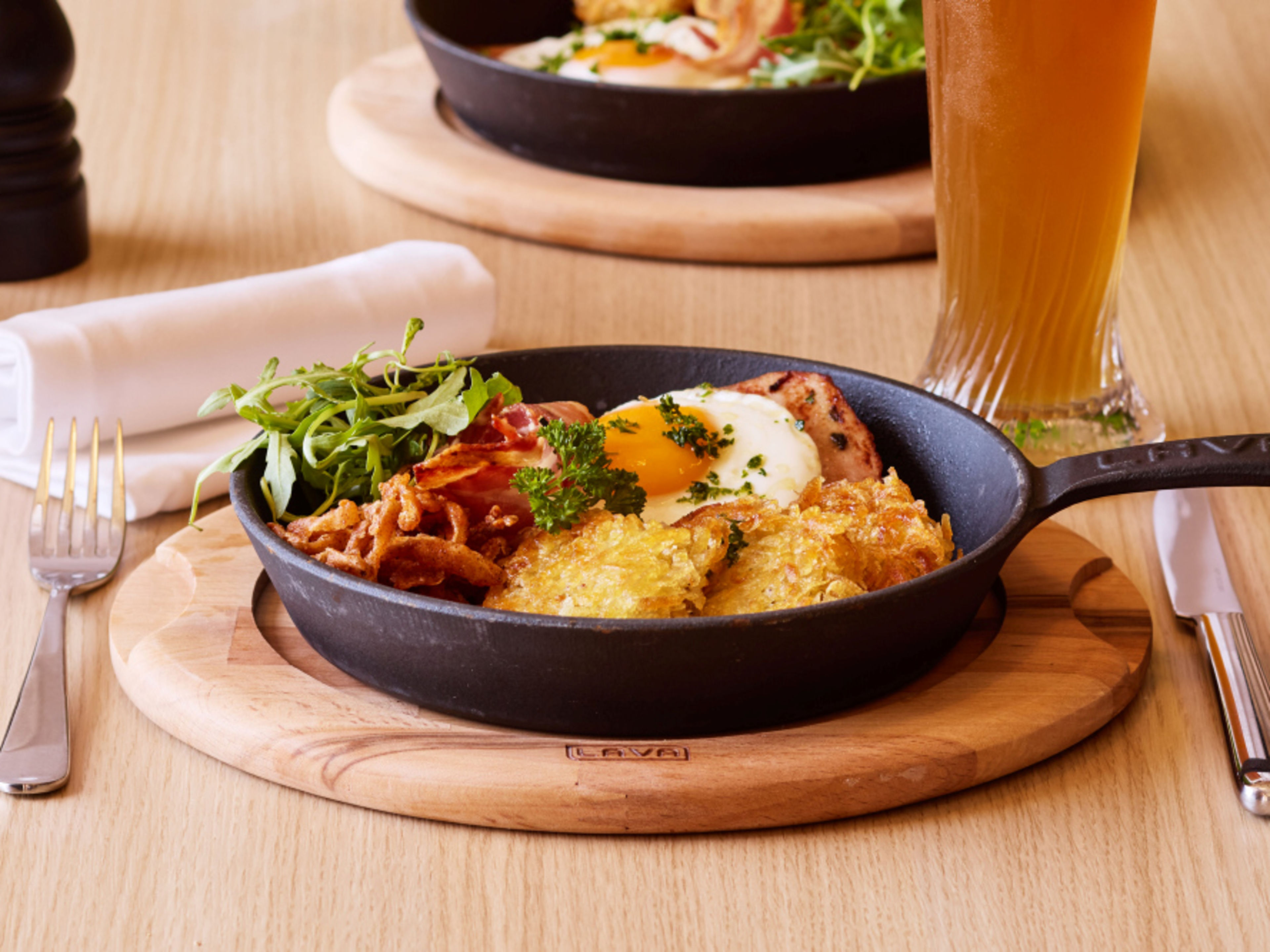 Rösti mit Spiegelei und Speck, serviert in einer schwarzen Pfanne. Rösti mit Spiegelei und Speck, serviert in einer schwarzen Pfanne.