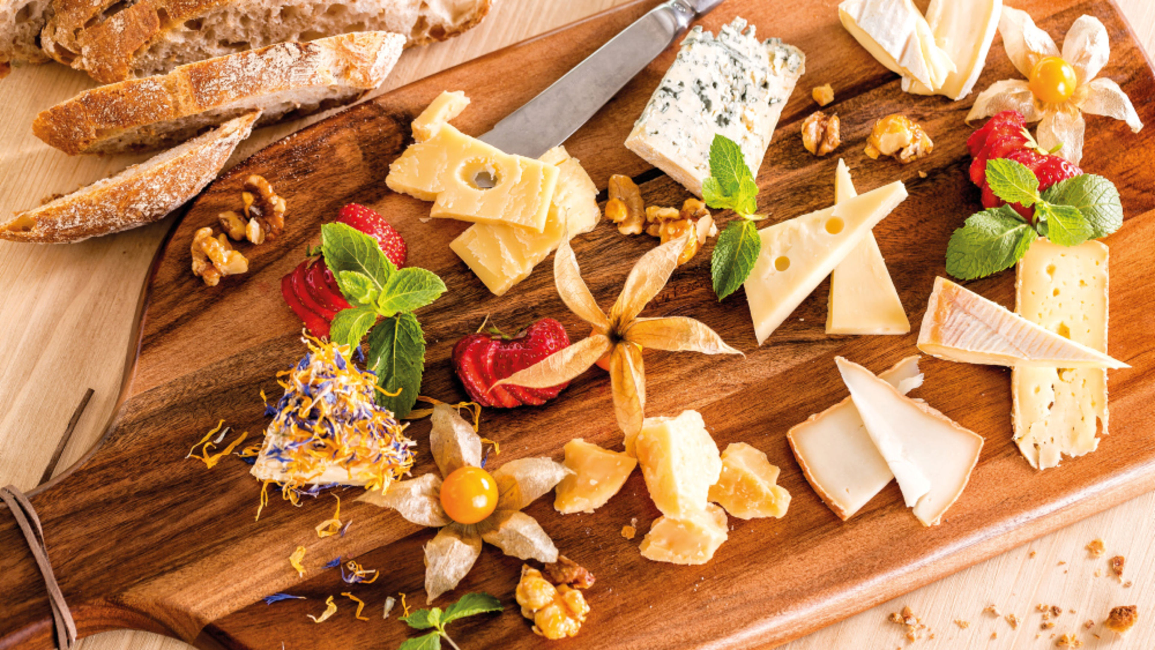 A cheese platter with bread, nuts, strawberries and mint. A cheese platter with bread, nuts, strawberries and mint.