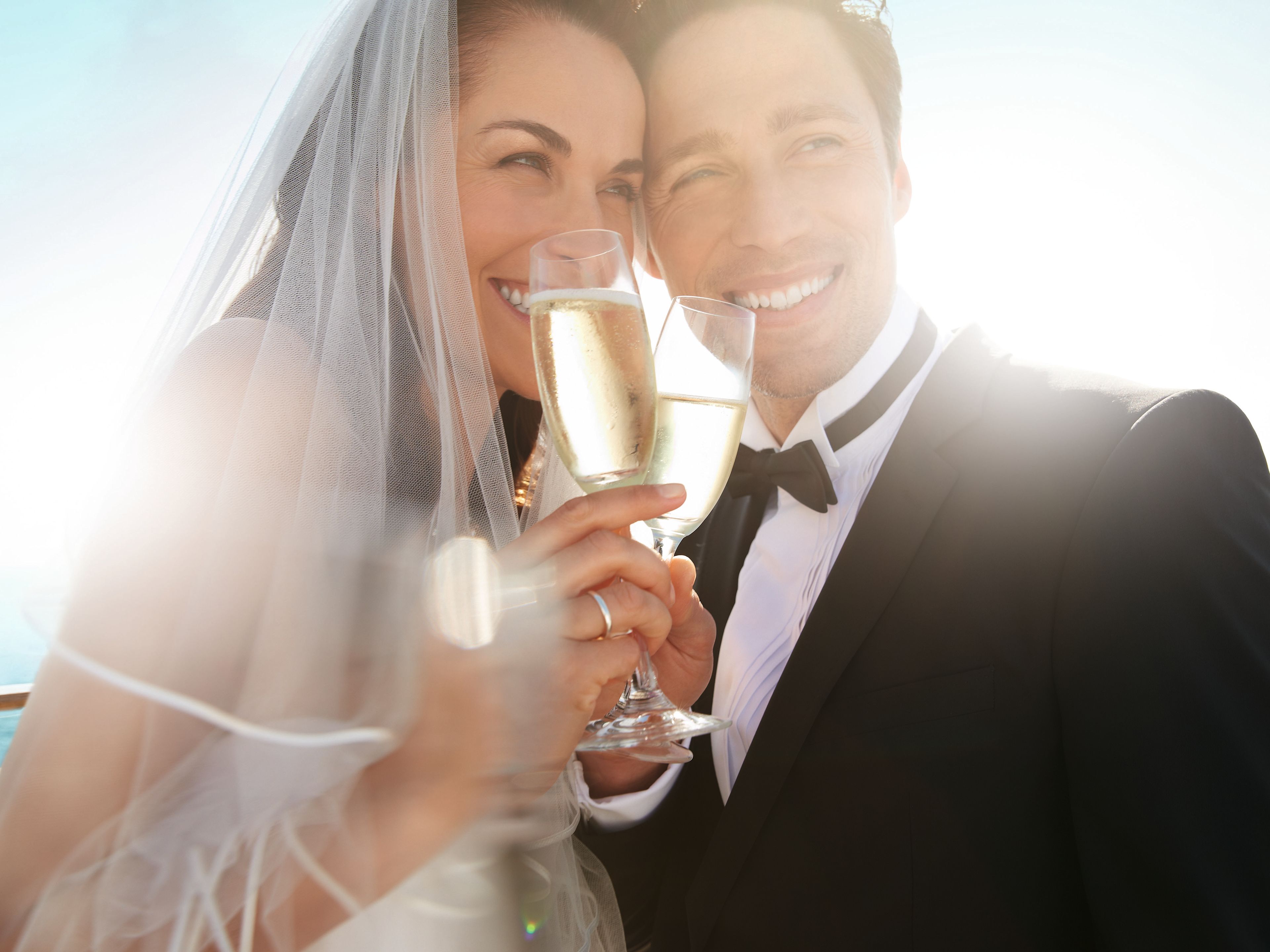 Bride and groom toasting with champagne, sunny day, sea background. Bride and groom toasting with champagne, sunny day, sea background.