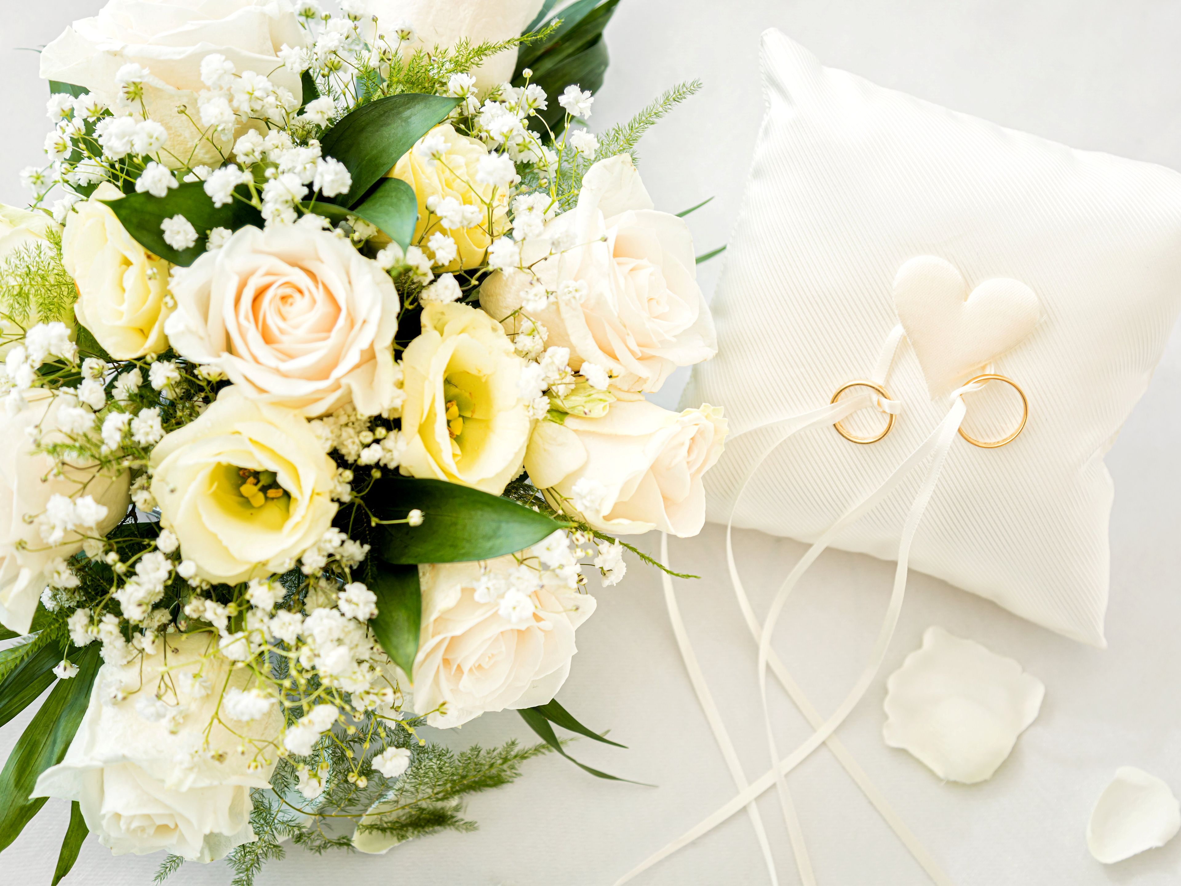Brautstrauß mit weißen Rosen und Eheringe auf Kissen. Brautstrauß mit weißen Rosen und Eheringe auf Kissen.