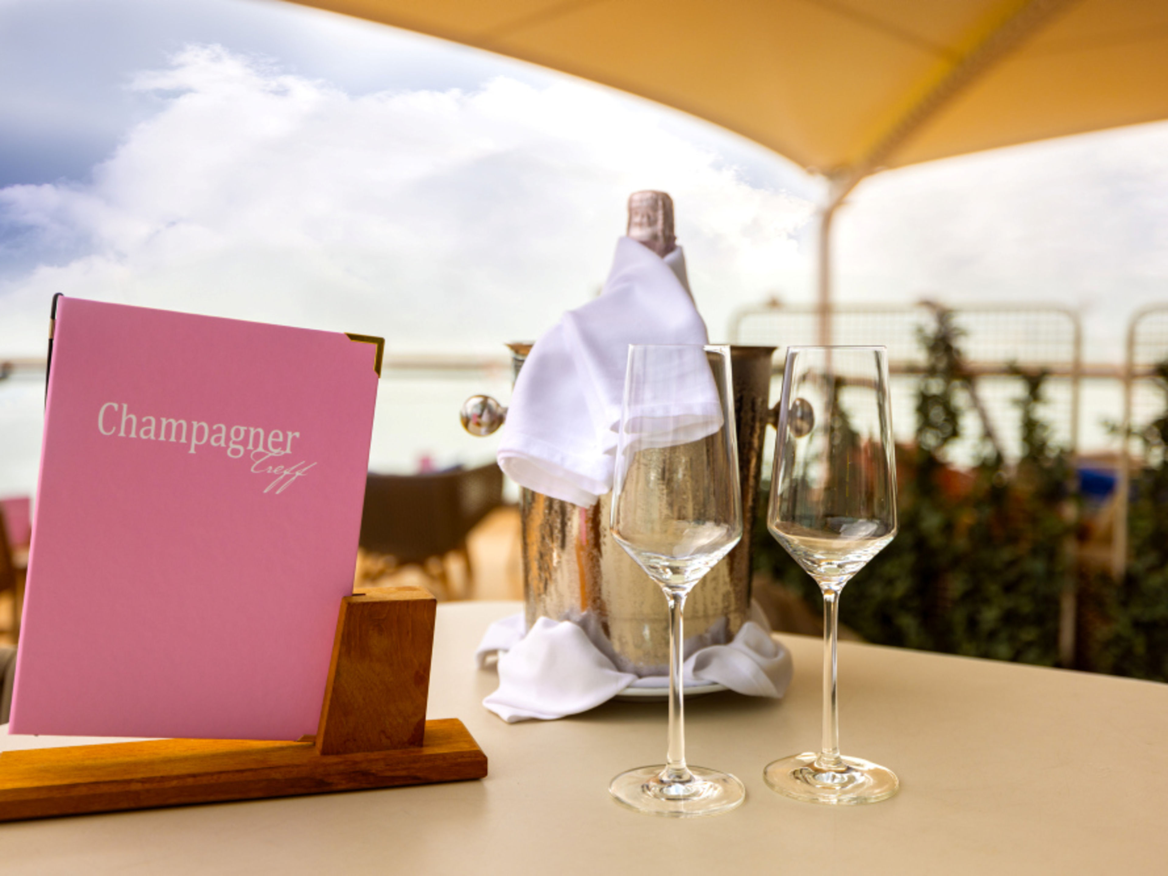 Champagne cooler with a bottle, two glasses and the Champagne Treff drinks menu Champagne cooler with a bottle, two glasses and the Champagne Treff drinks menu
