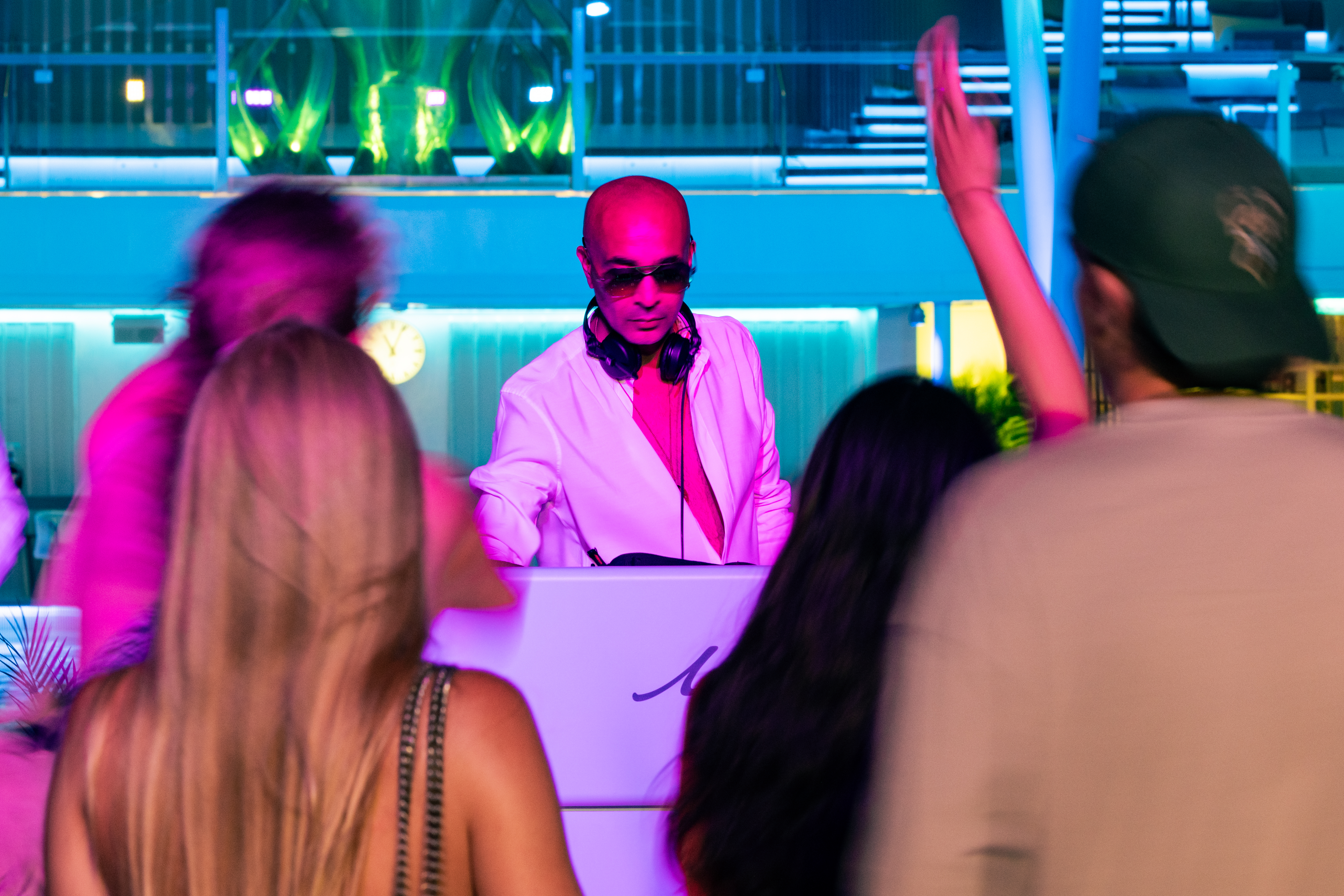 DJ spielt draußen auf dem Pooldeck mit tanzenden Gästen. 