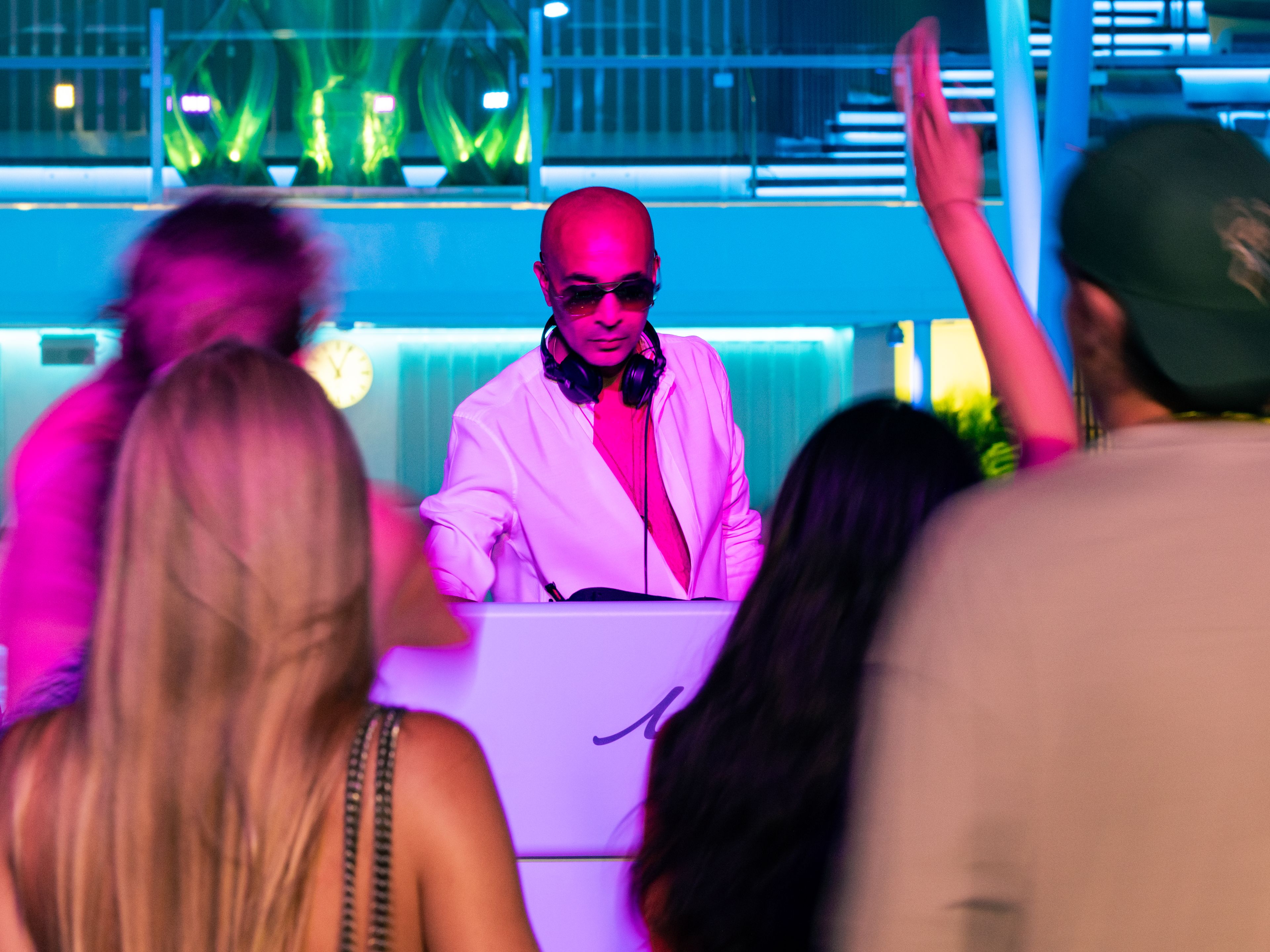 DJ spielt draußen auf dem Pooldeck mit tanzenden Gästen. DJ spielt draußen auf dem Pooldeck mit tanzenden Gästen.