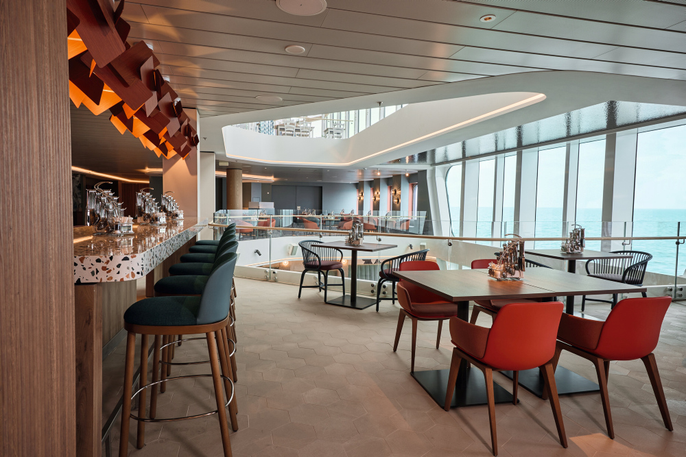 Moderne Kreuzfahrtschiff-Lounge mit Bar, roten Sesseln und Meerblick durch Panoramafenster