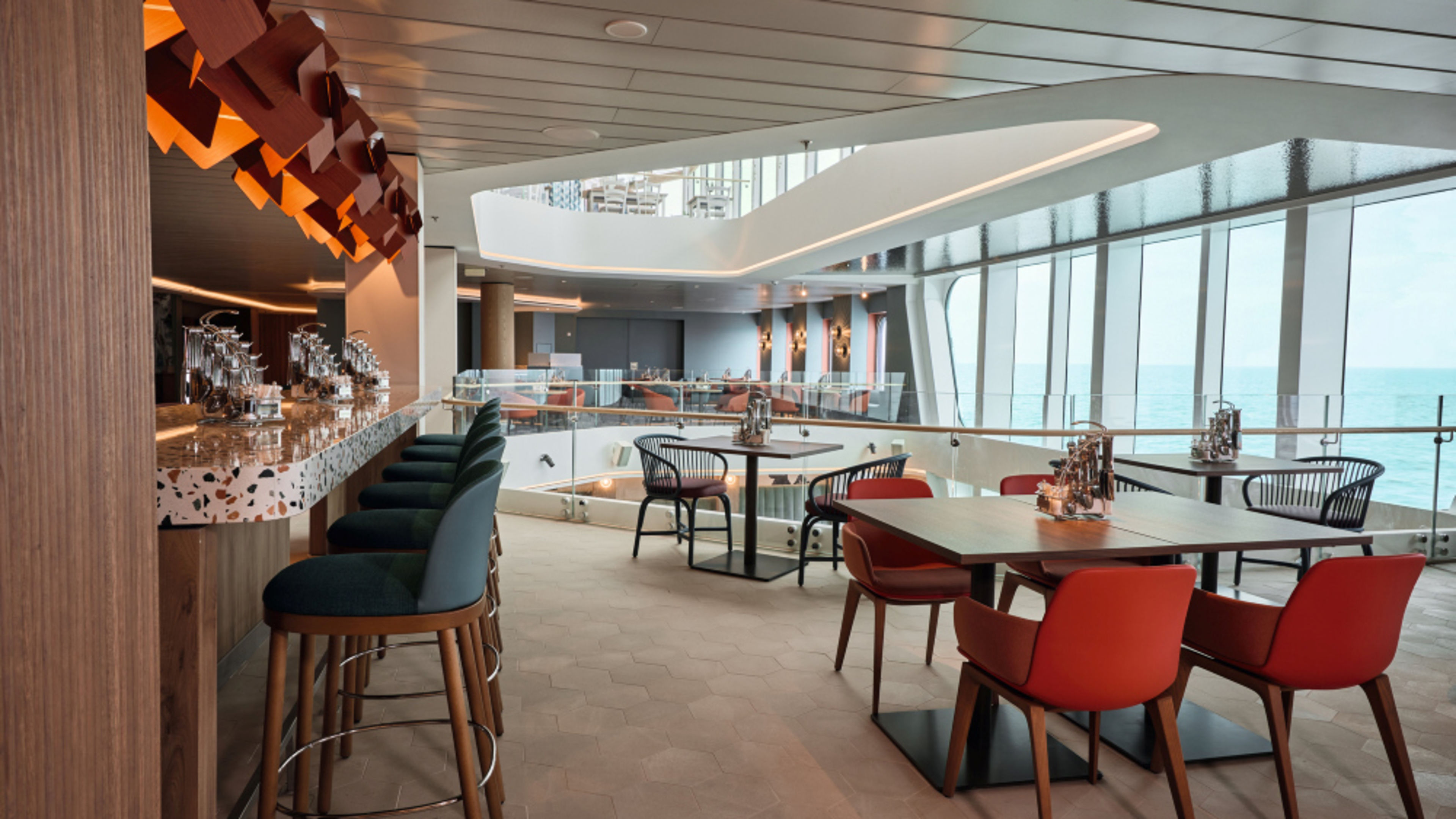 Moderne Kreuzfahrtschiff-Lounge mit Bar, roten Sesseln und Meerblick durch Panoramafenster Moderne Kreuzfahrtschiff-Lounge mit Bar, roten Sesseln und Meerblick durch Panoramafenster