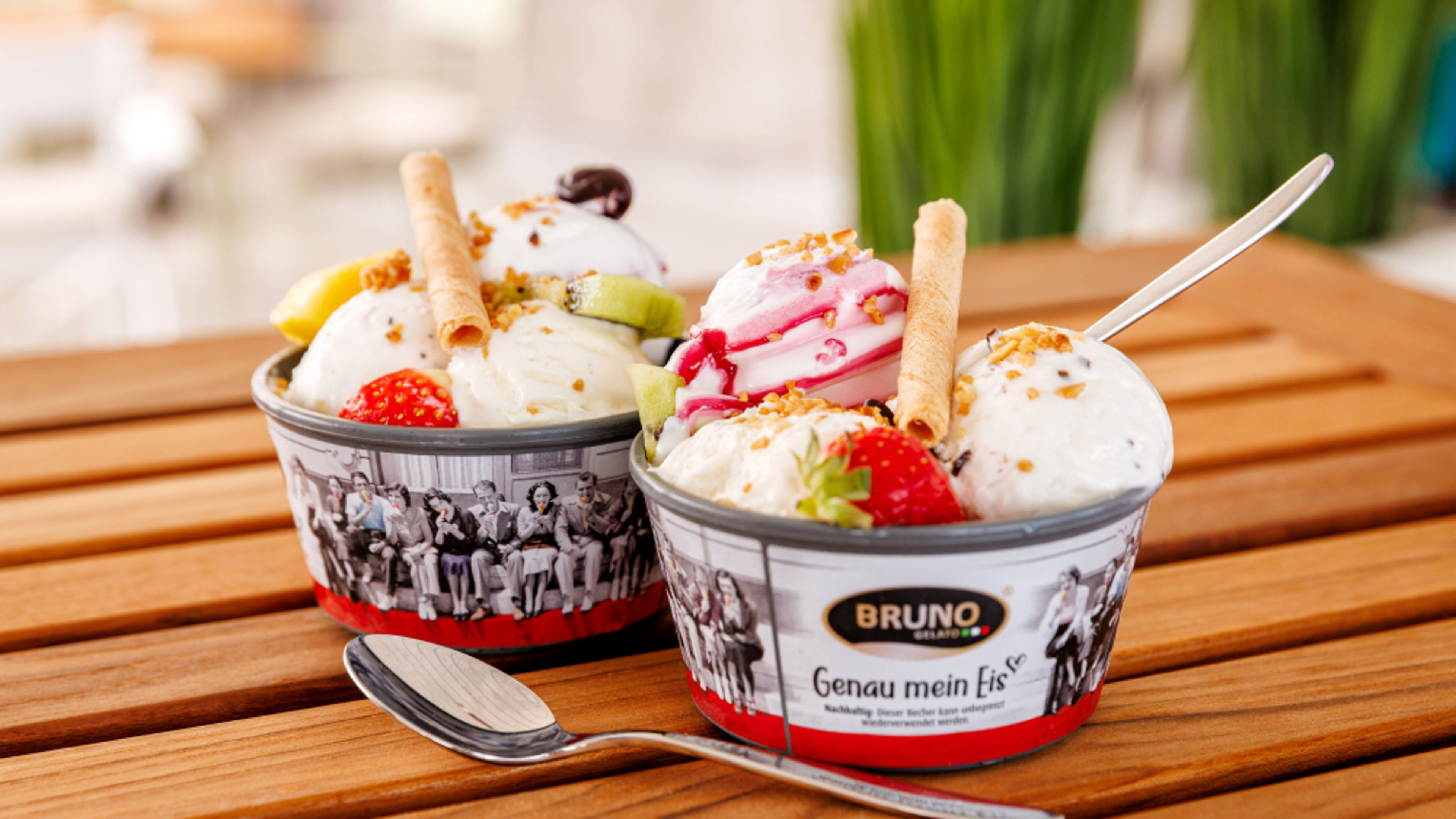 Zwei Becher Eiscreme mit Früchten und Waffeln auf Holztisch. Zwei Becher Eiscreme mit Früchten und Waffeln auf Holztisch.