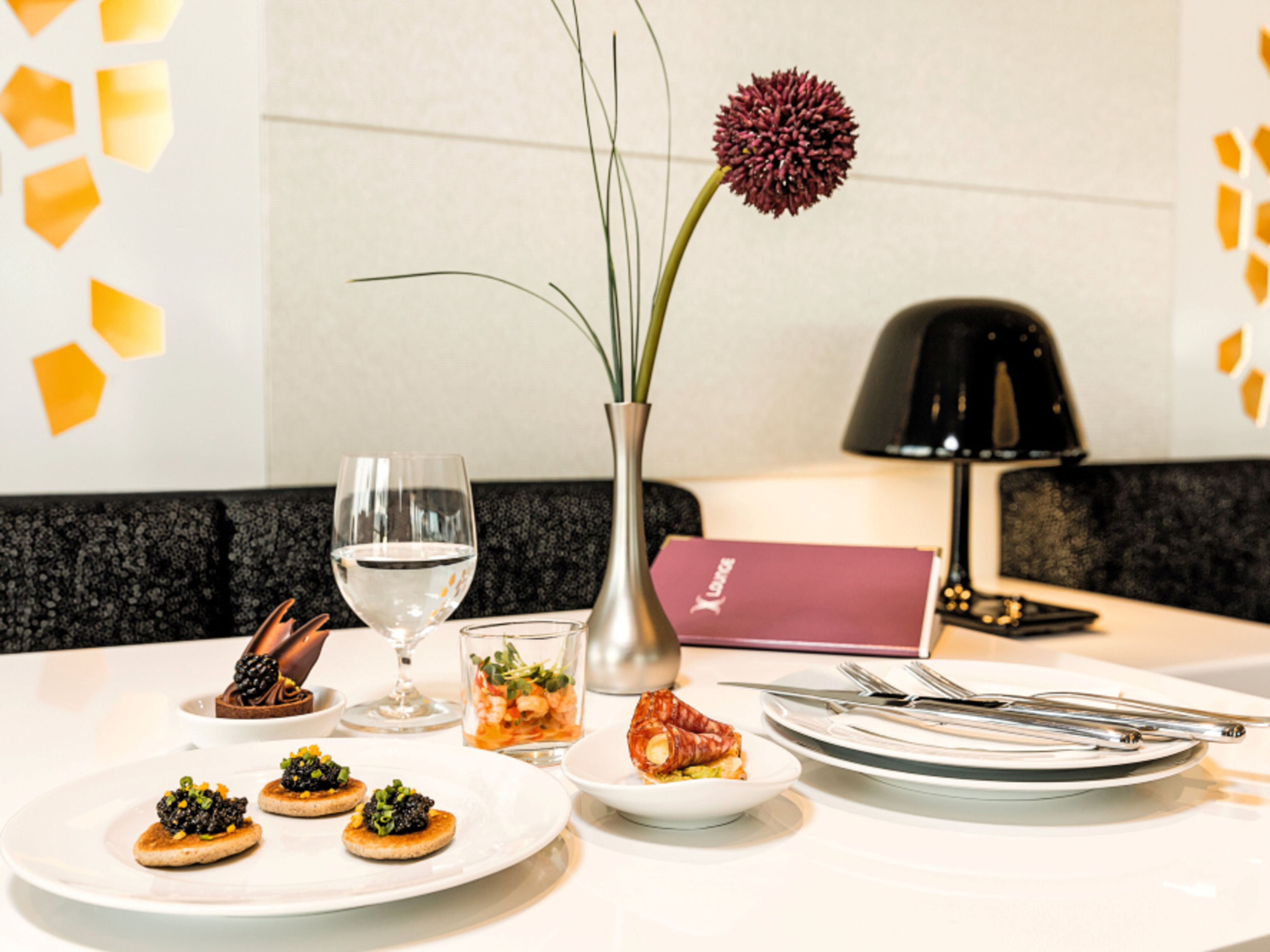 An elegantly laid table at the X-Lounge restaurant, featuring starters, a wine glass and a vase of flowers. An elegantly laid table at the X-Lounge restaurant, featuring starters, a wine glass and a vase of flowers.