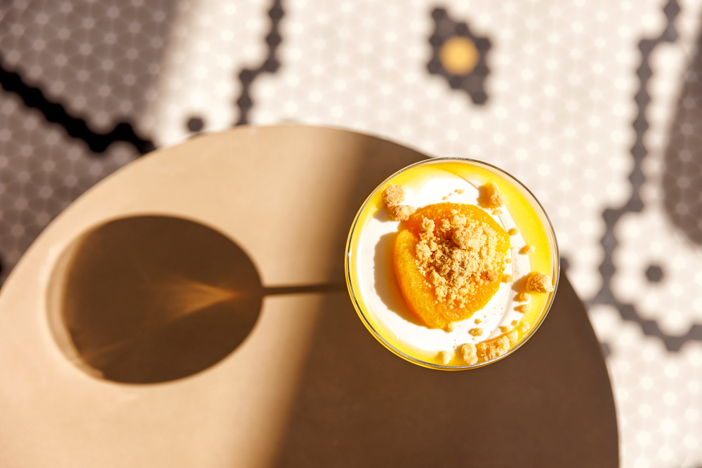 Panna cotta with apricot and crumble topping on the table, casting a shadow.