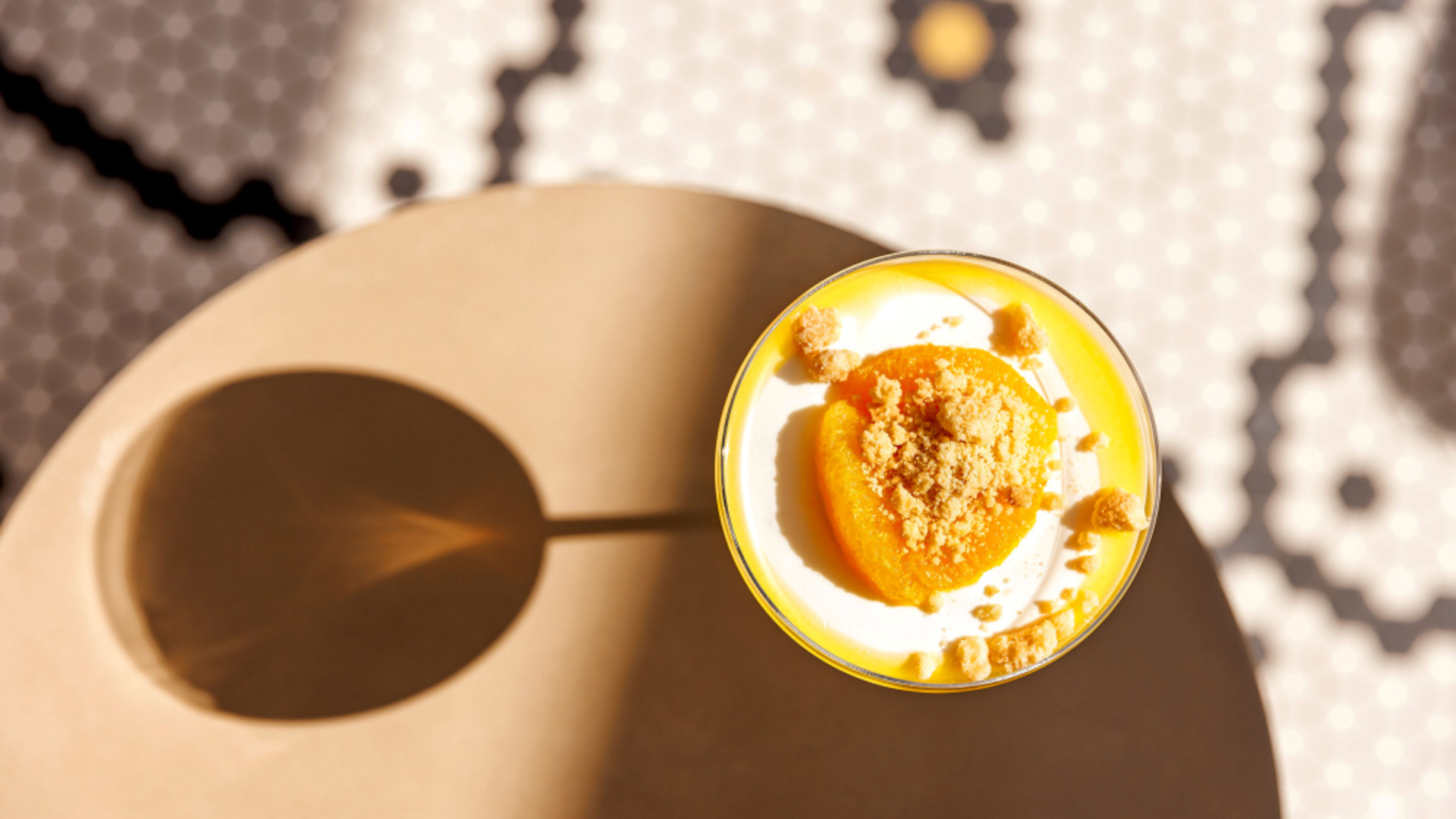 Panna cotta with apricot and crumble topping on the table, casting a shadow. Panna cotta with apricot and crumble topping on the table, casting a shadow.