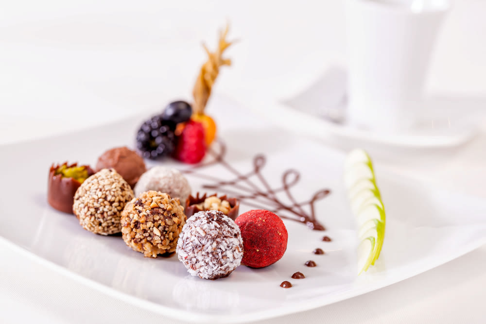 Pralinen auf weißem Teller mit Beeren und Schokoladendekor. Pralinen auf weißem Teller mit Beeren und Schokoladendekor.