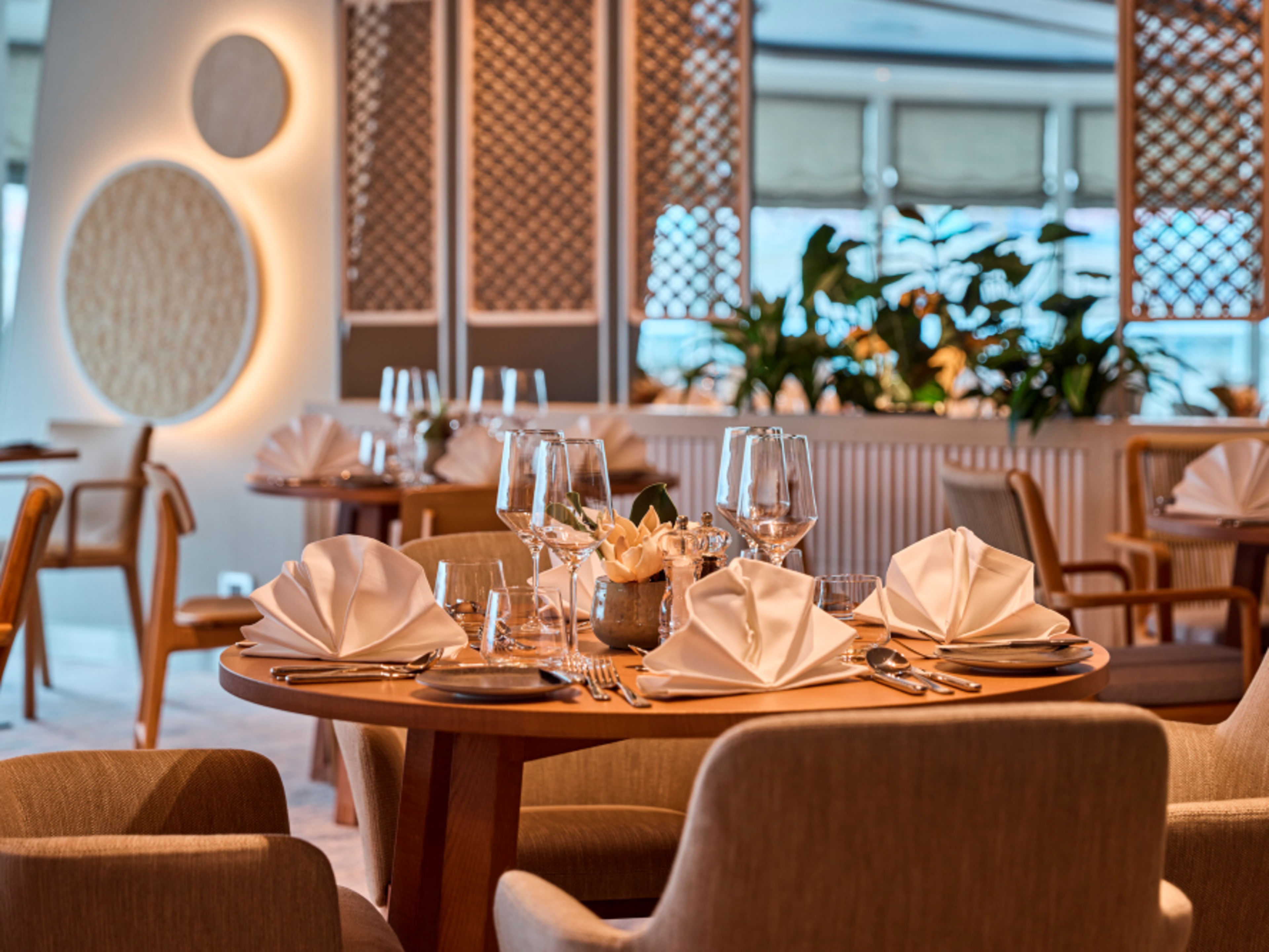 Elegant gedeckter Tisch in hellem Restaurant X-Coast mit Weingläsern und weißen Stoffservietten. Elegant gedeckter Tisch in hellem Restaurant X-Coast mit Weingläsern und weißen Stoffservietten.