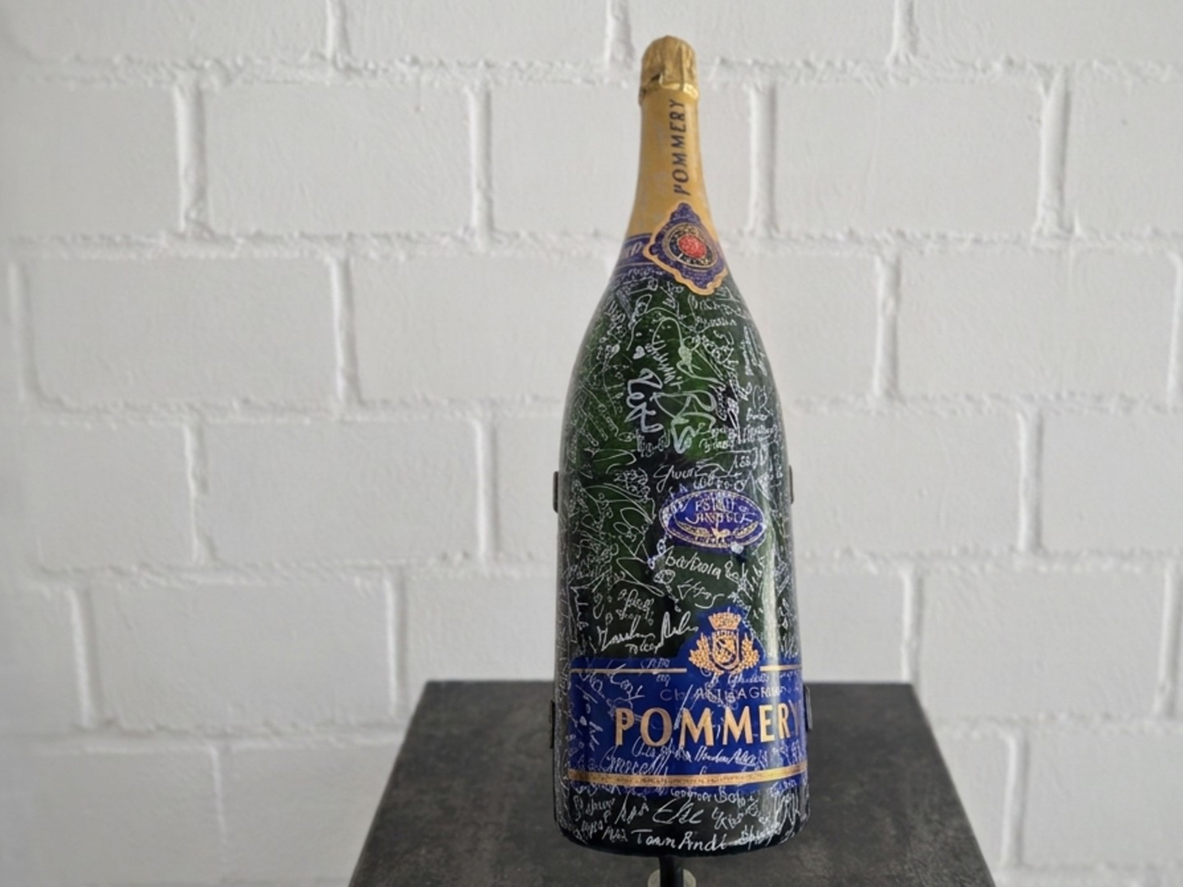 Große grüne Pommery Champagnerflasche mit vielen Autogrammen auf einem Sockel. Große grüne Pommery Champagnerflasche mit vielen Autogrammen auf einem Sockel.