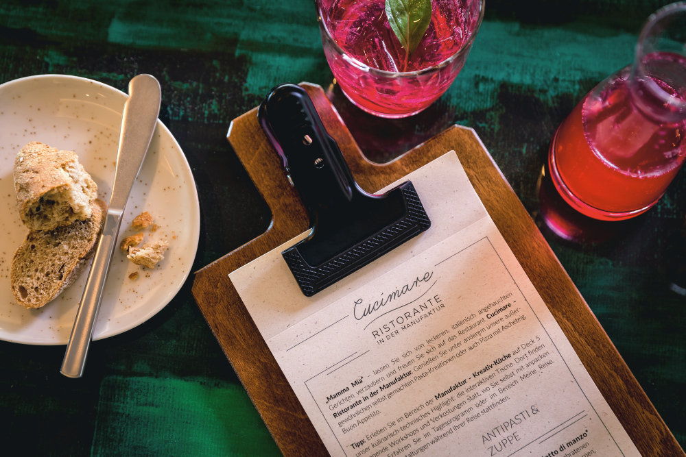 Cucimare menu on a wooden board, bread on a plate, red drink.