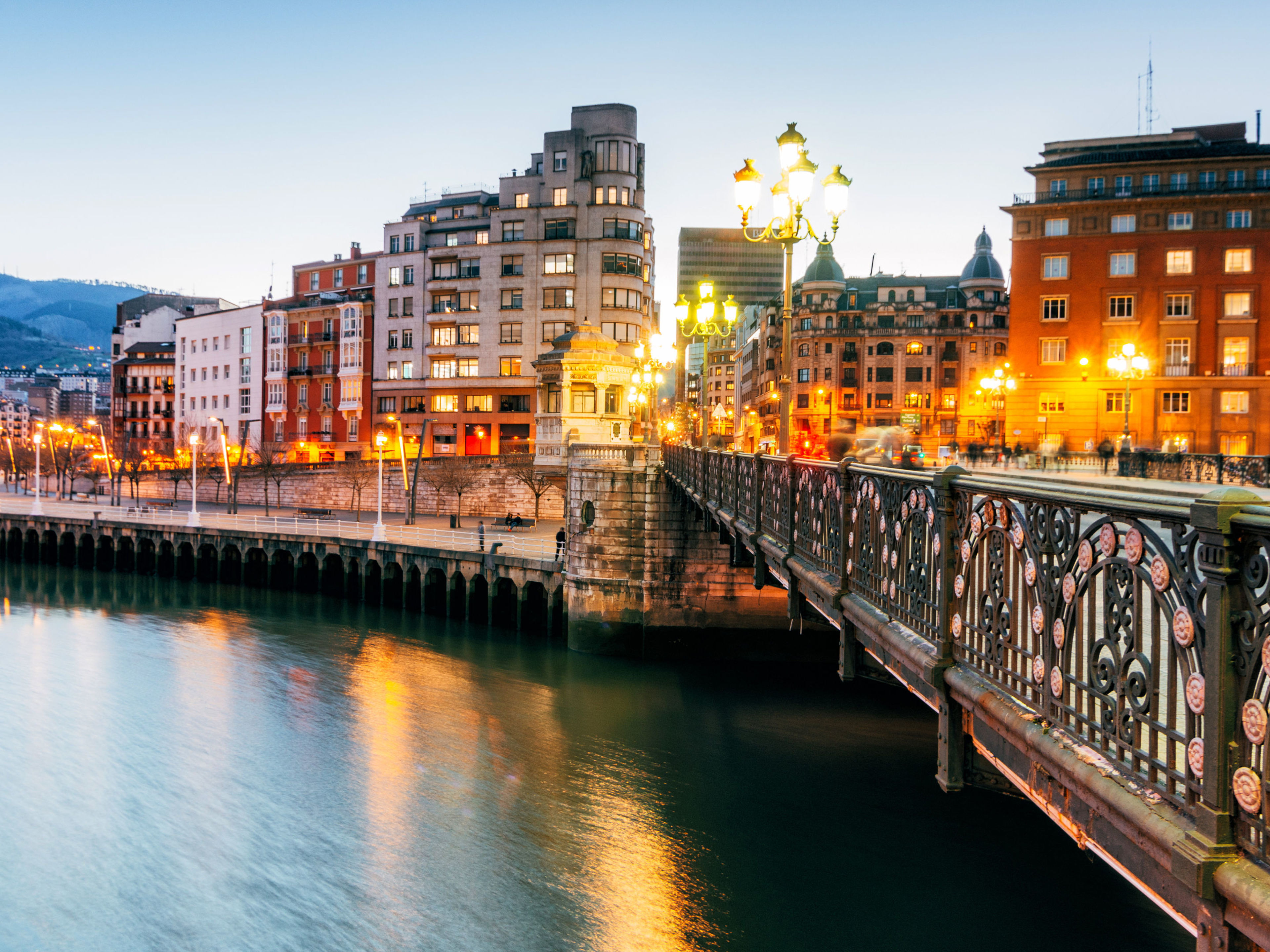 Brücke und beleuchtete Gebäude am Flussufer in Bilbao bei Dämmerung. Brücke und beleuchtete Gebäude am Flussufer in Bilbao bei Dämmerung.