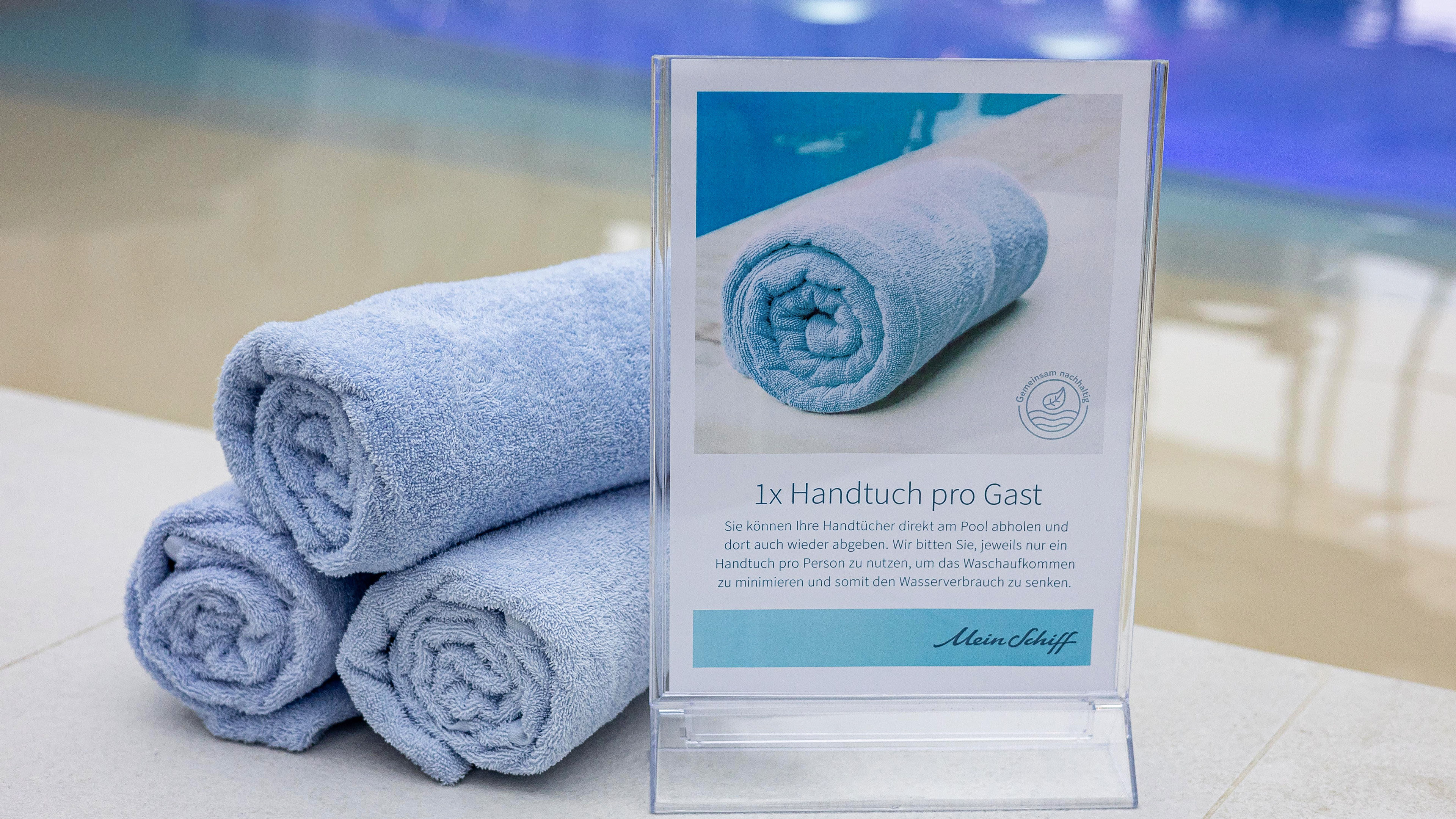 Gerollte blaue Handtücher neben Schild mit Hinweistext.