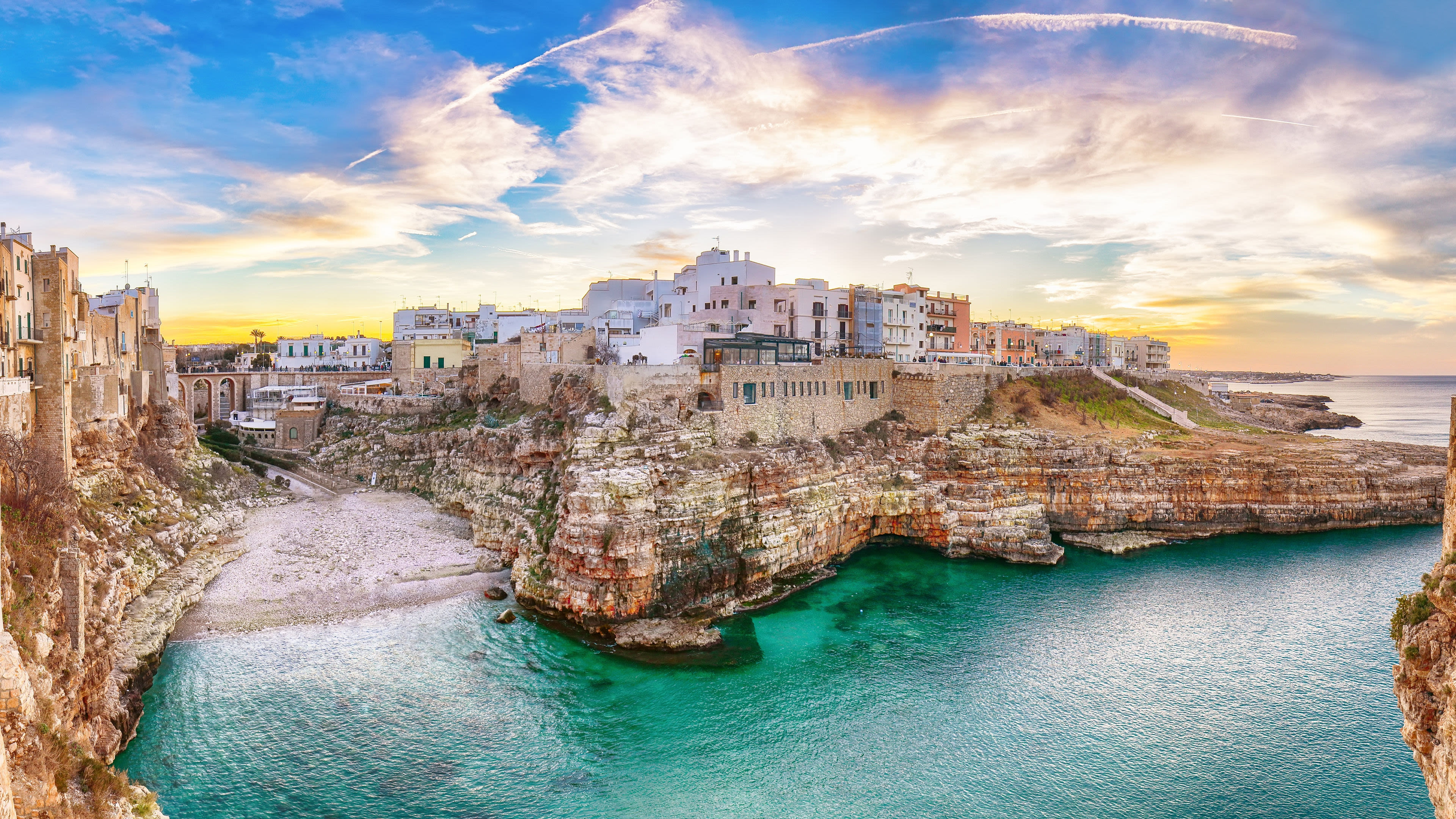 Küstenstadt Polignano a Mare, Italien, bei Sonnenuntergang, türkisfarbenes Meer, historische Gebäude. Küstenstadt Polignano a Mare, Italien, bei Sonnenuntergang, türkisfarbenes Meer, historische Gebäude.
