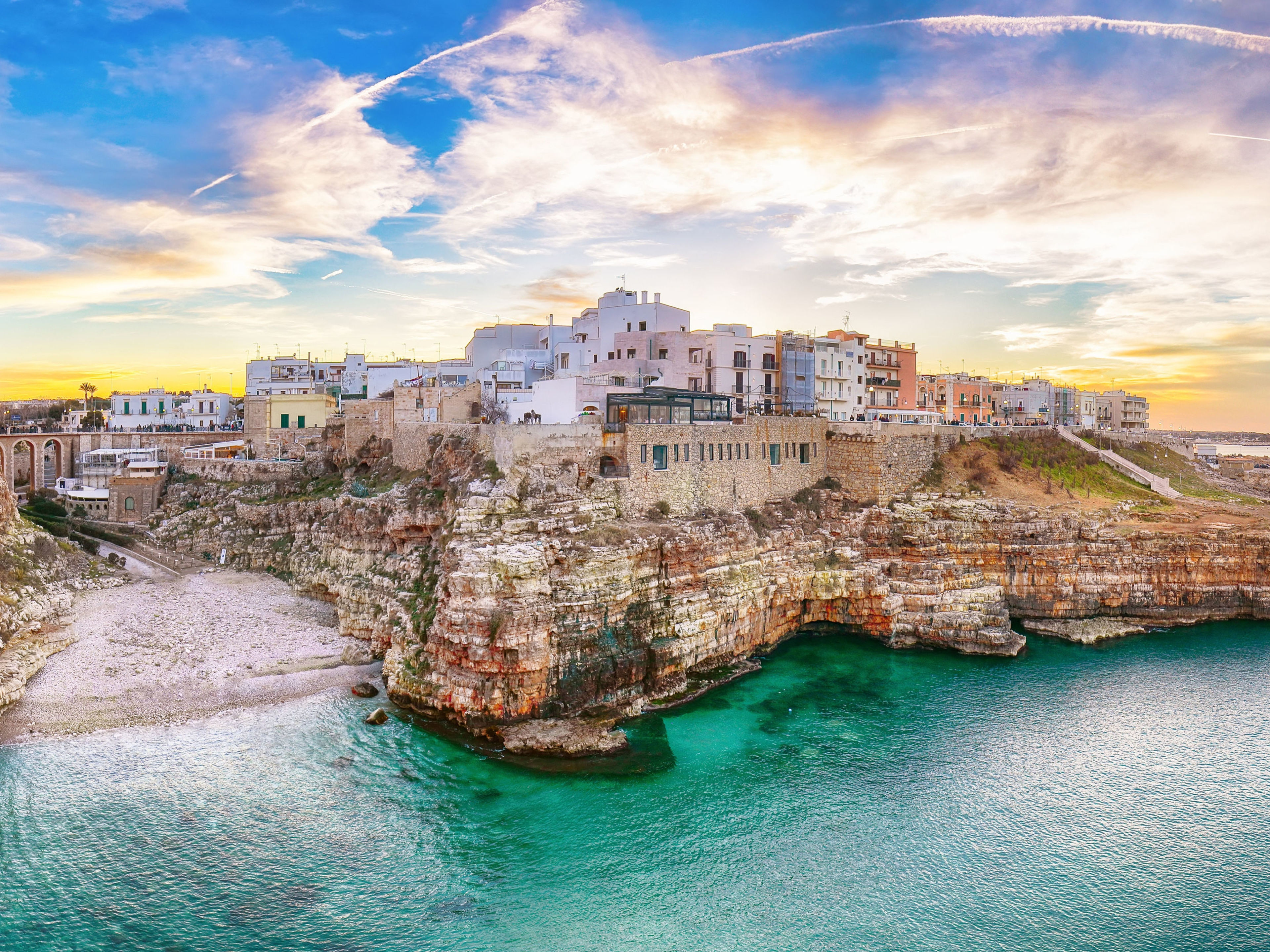 Küstenstadt Polignano a Mare, Italien, bei Sonnenuntergang, türkisfarbenes Meer, historische Gebäude. Küstenstadt Polignano a Mare, Italien, bei Sonnenuntergang, türkisfarbenes Meer, historische Gebäude.
