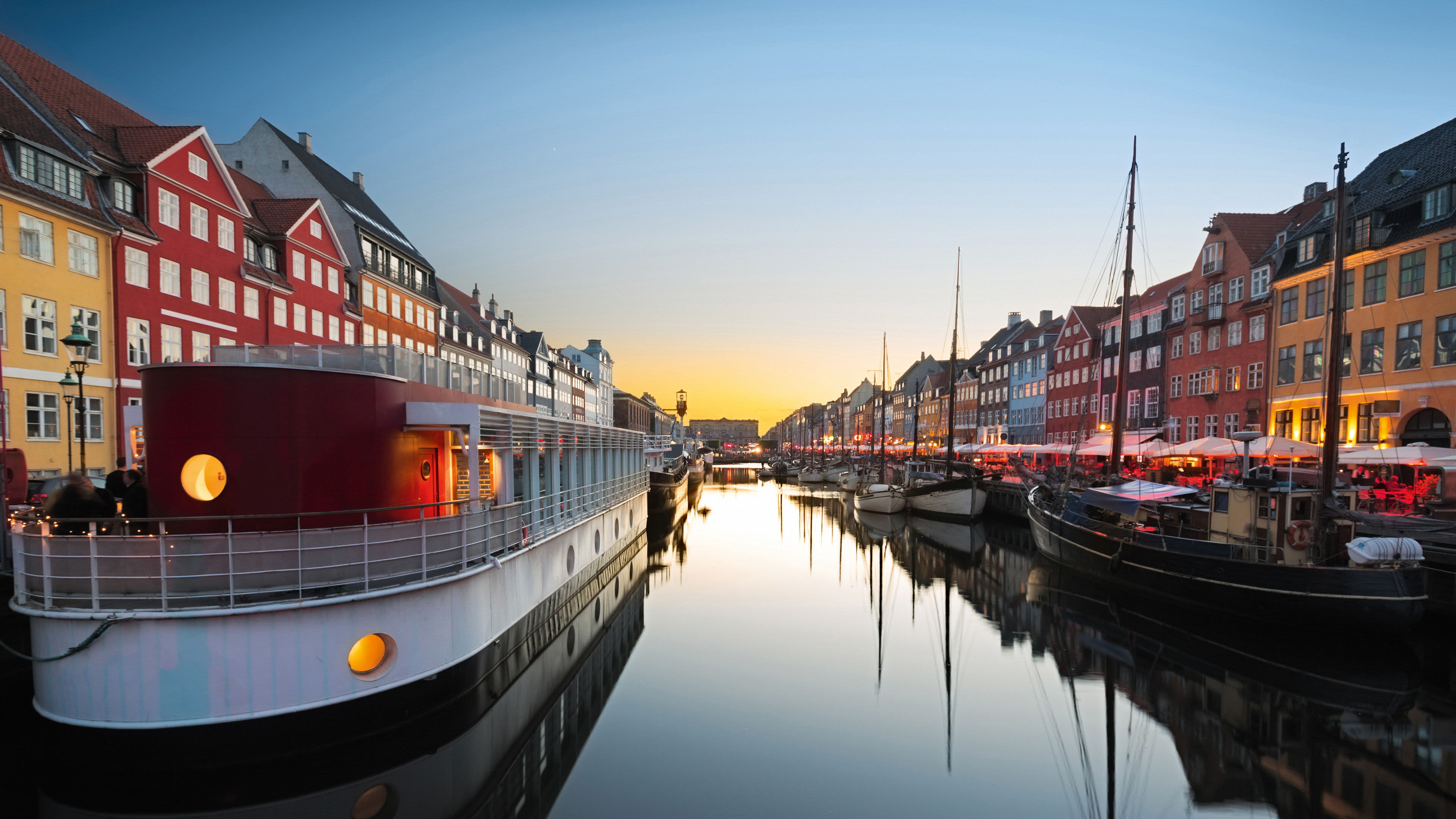 Bunte Häuser und Boote am Nyhavn-Kanal in Kopenhagen bei Sonnenuntergang.