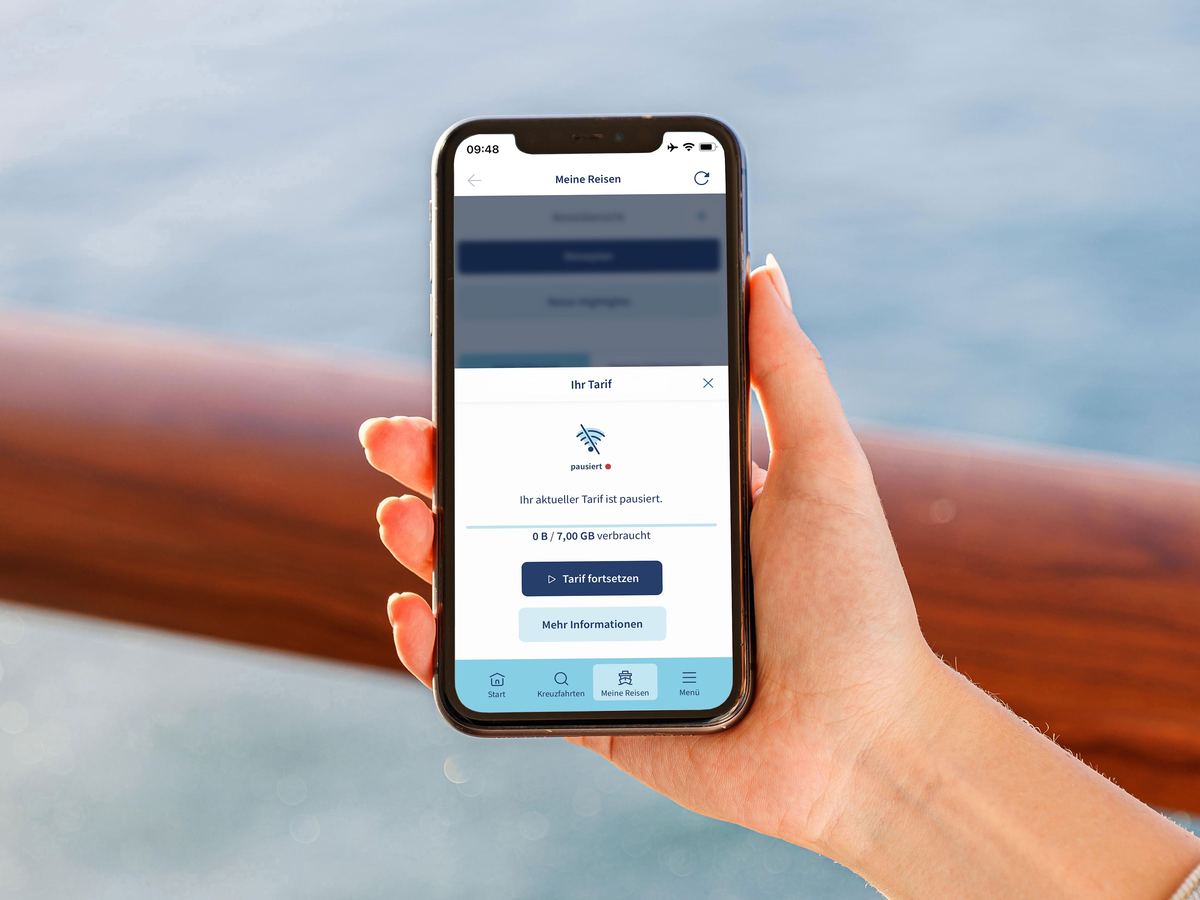 Hand hält Smartphone mit App, Meer im Hintergrund. Hand hält Smartphone mit App, Meer im Hintergrund.