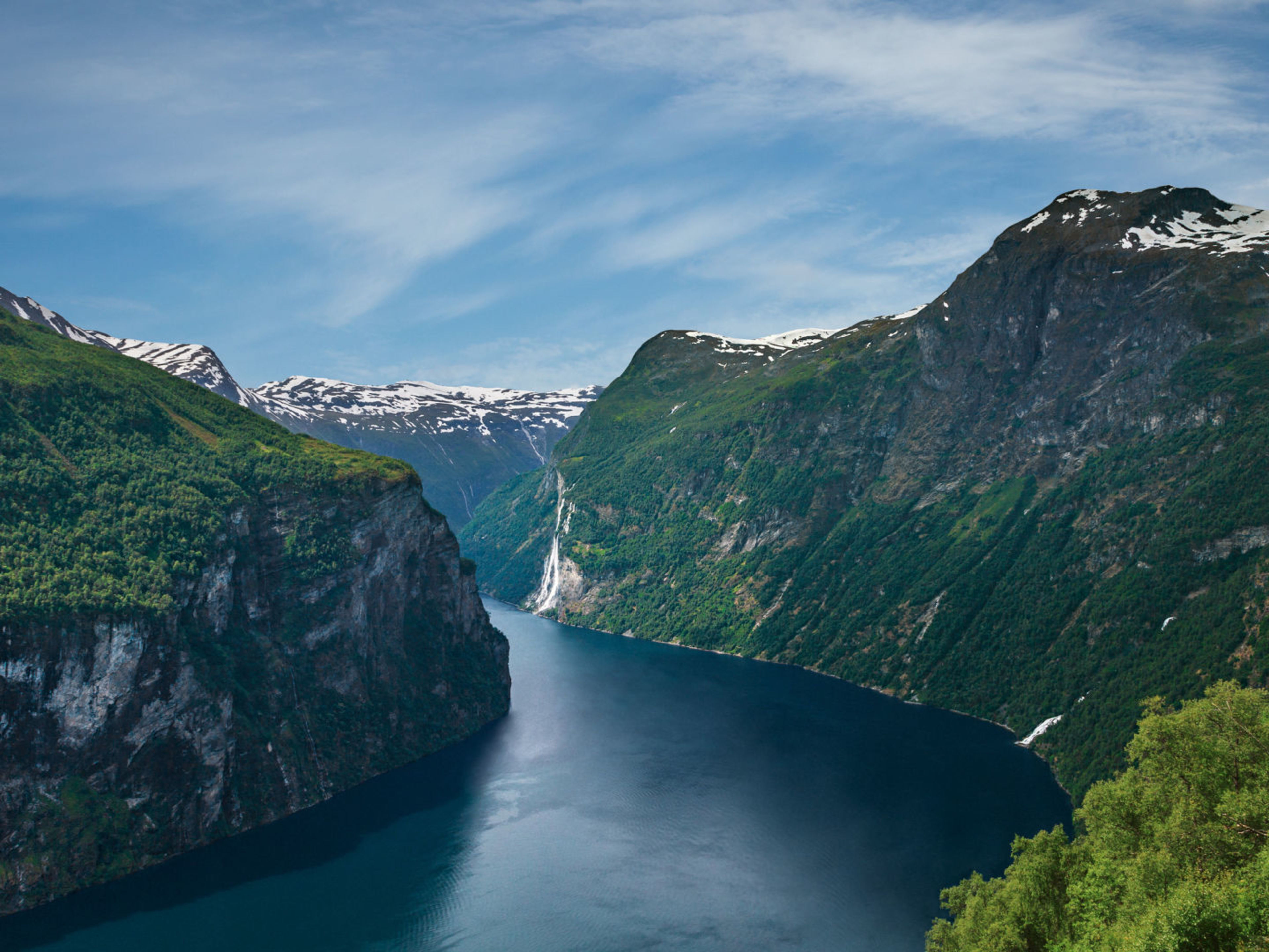 Norwegischer Fjord mit Wasserfall, umgeben von grünen Bergen und blauem Himmel. Norwegischer Fjord mit Wasserfall, umgeben von grünen Bergen und blauem Himmel.