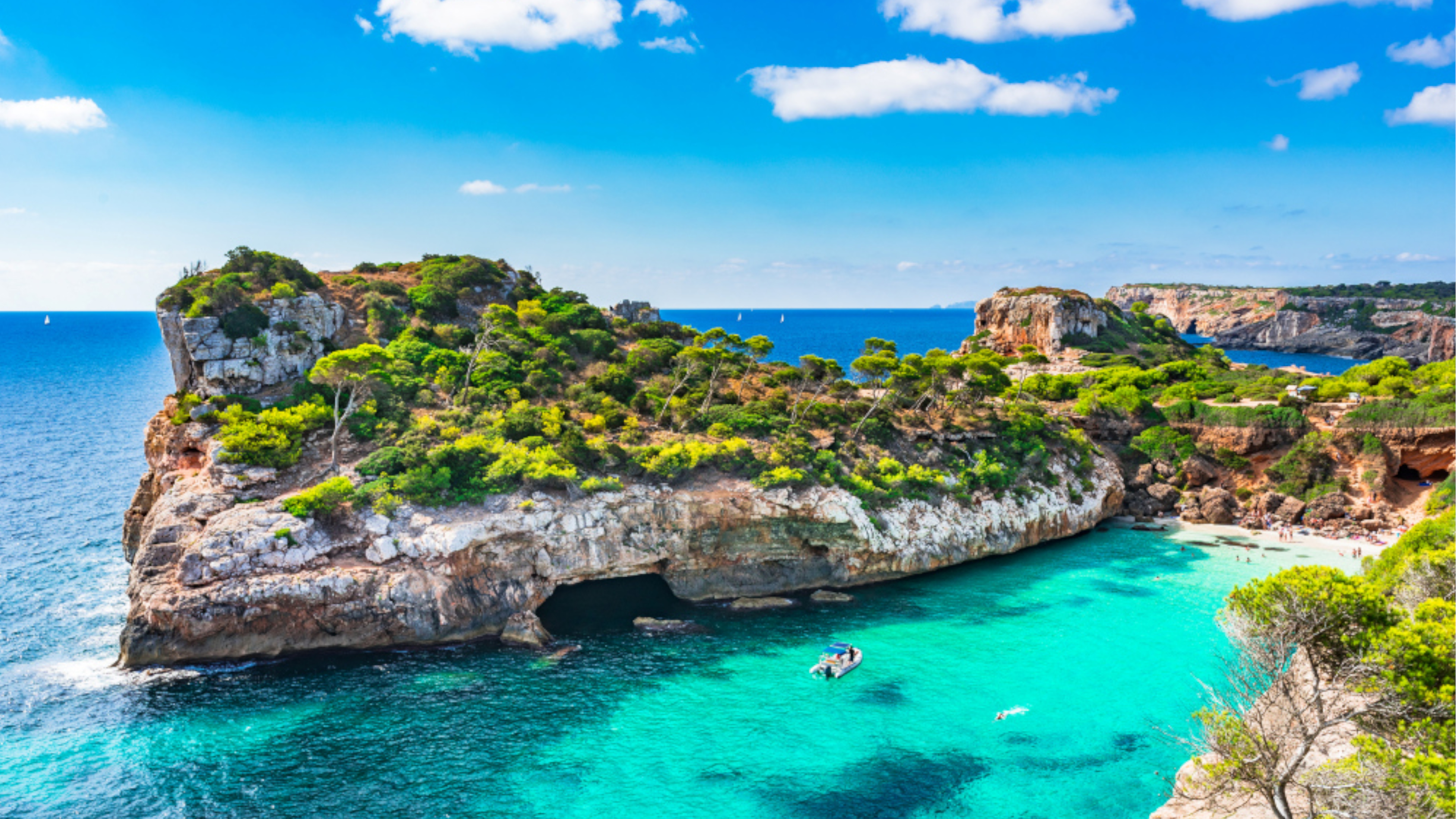 Küste von Mallorca mit türkisfarbenem Wasser und Boot.