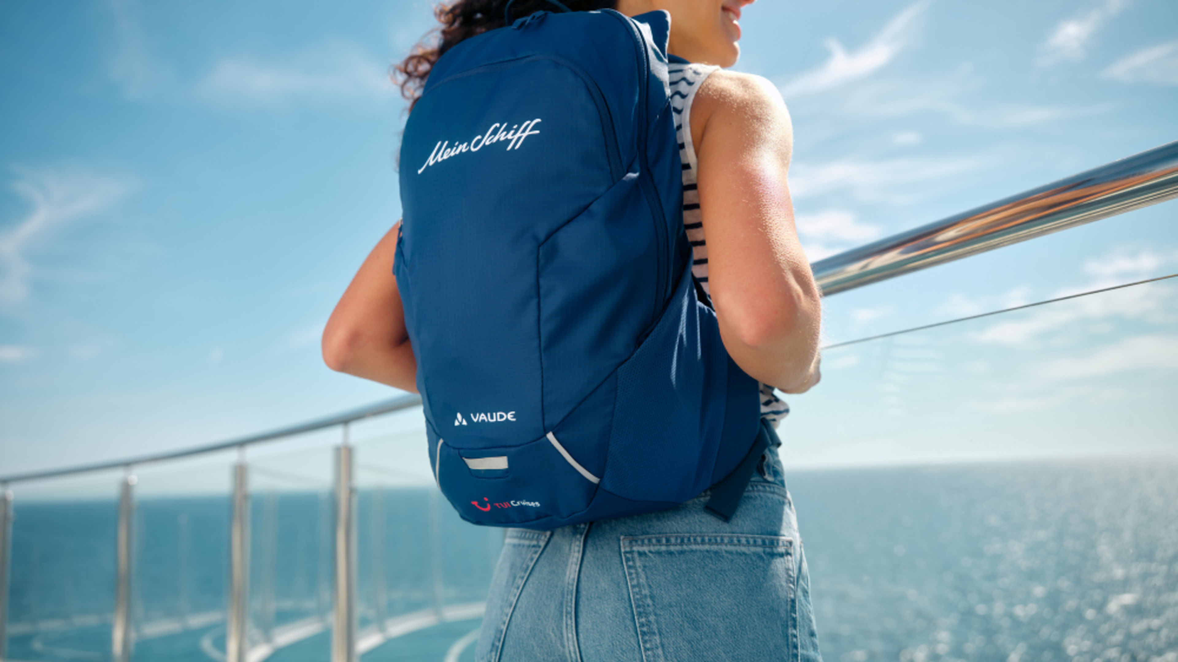 Frau mit blauem Rucksack auf Kreuzfahrtschiff, Meer im Hintergrund. Frau mit blauem Rucksack auf Kreuzfahrtschiff, Meer im Hintergrund.