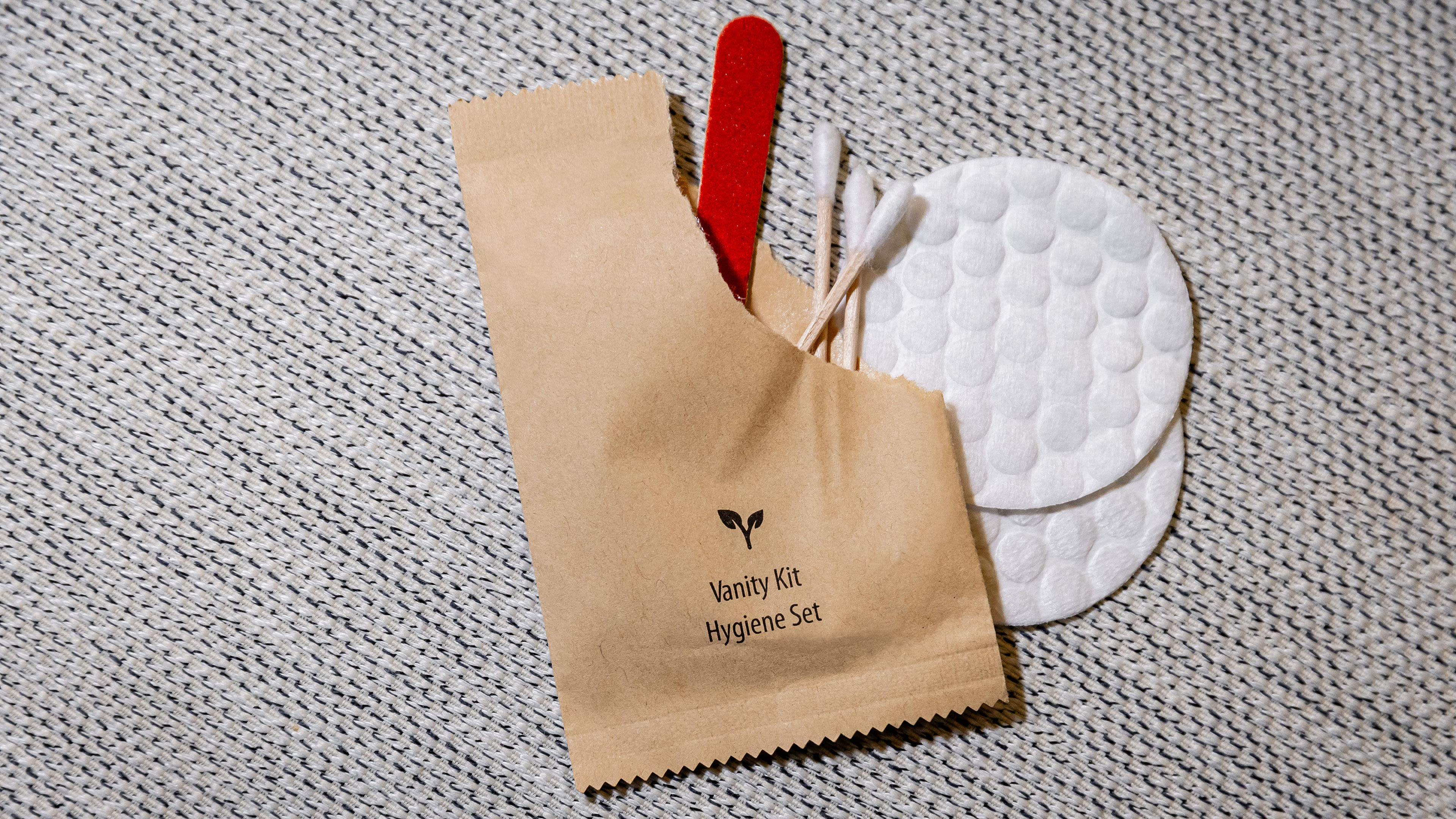 Hygieneset mit Wattestäbchen, Wattepads und Nagelfeile auf Stoff.