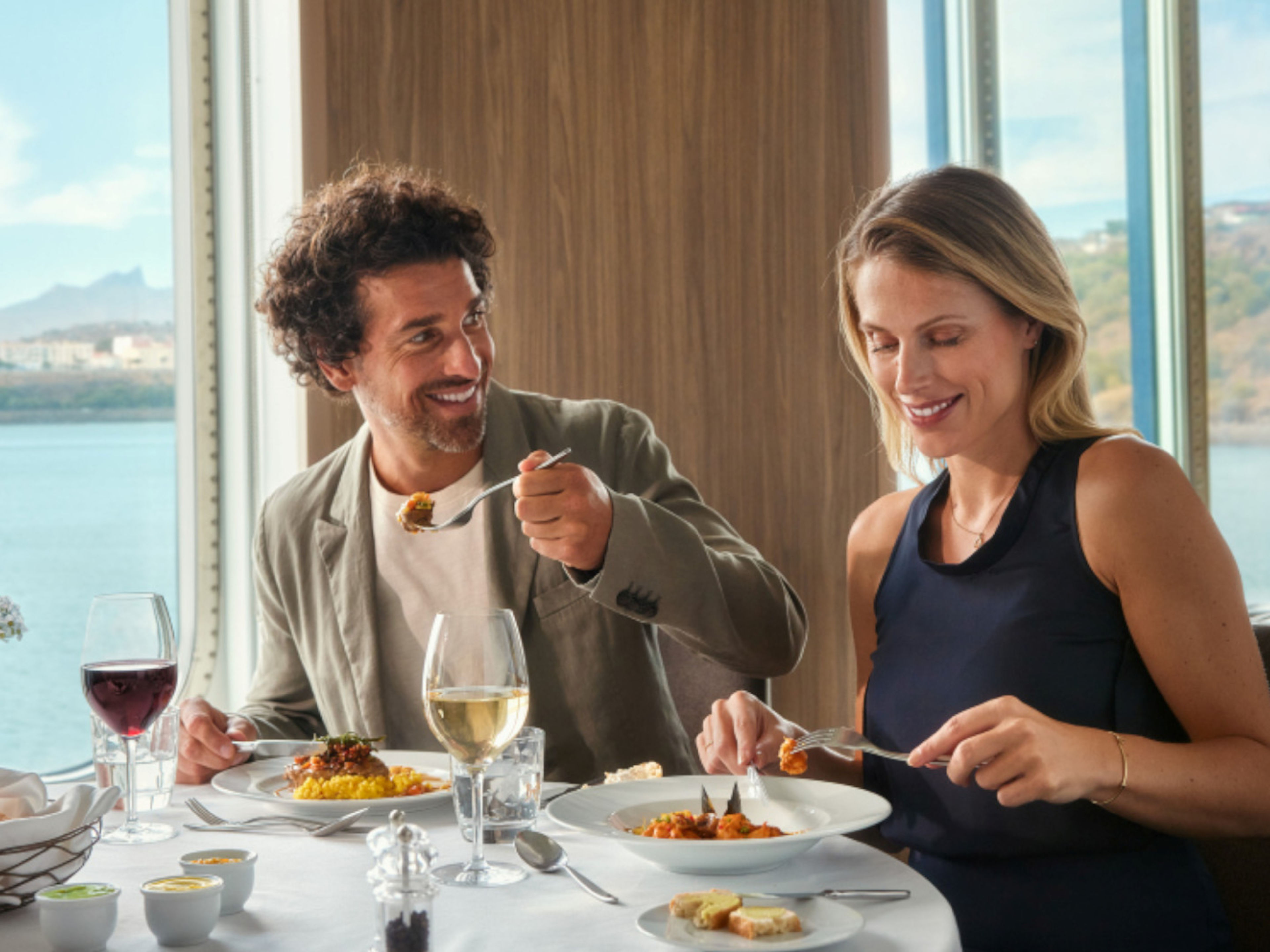 Paar genießt Mittagessen mit Wein am Fenster, Meerblick. Paar genießt Mittagessen mit Wein am Fenster, Meerblick.