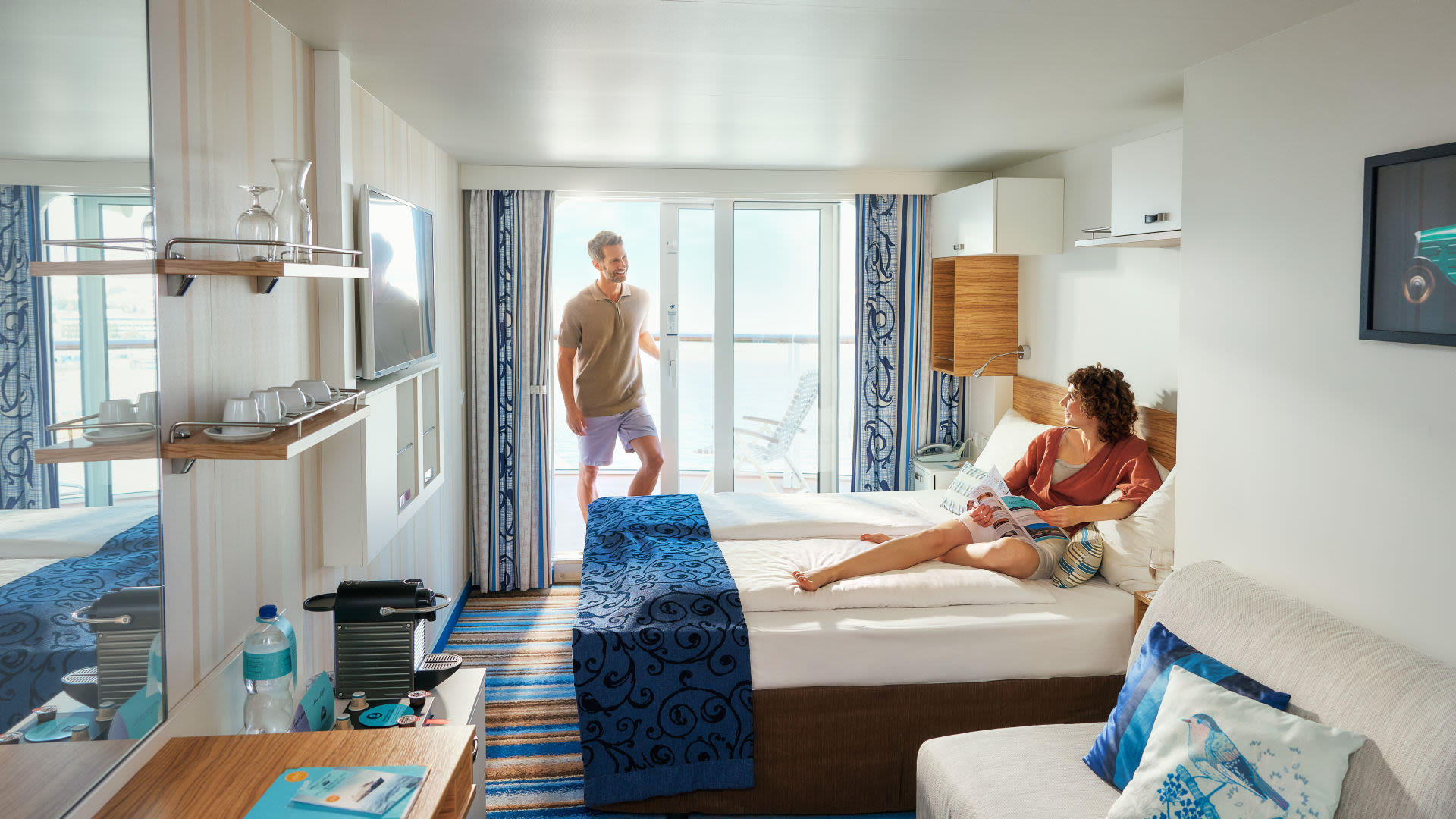Paar entspannt in moderner Kreuzfahrtkabine mit Balkon und Meerblick. Paar entspannt in moderner Kreuzfahrtkabine mit Balkon und Meerblick.