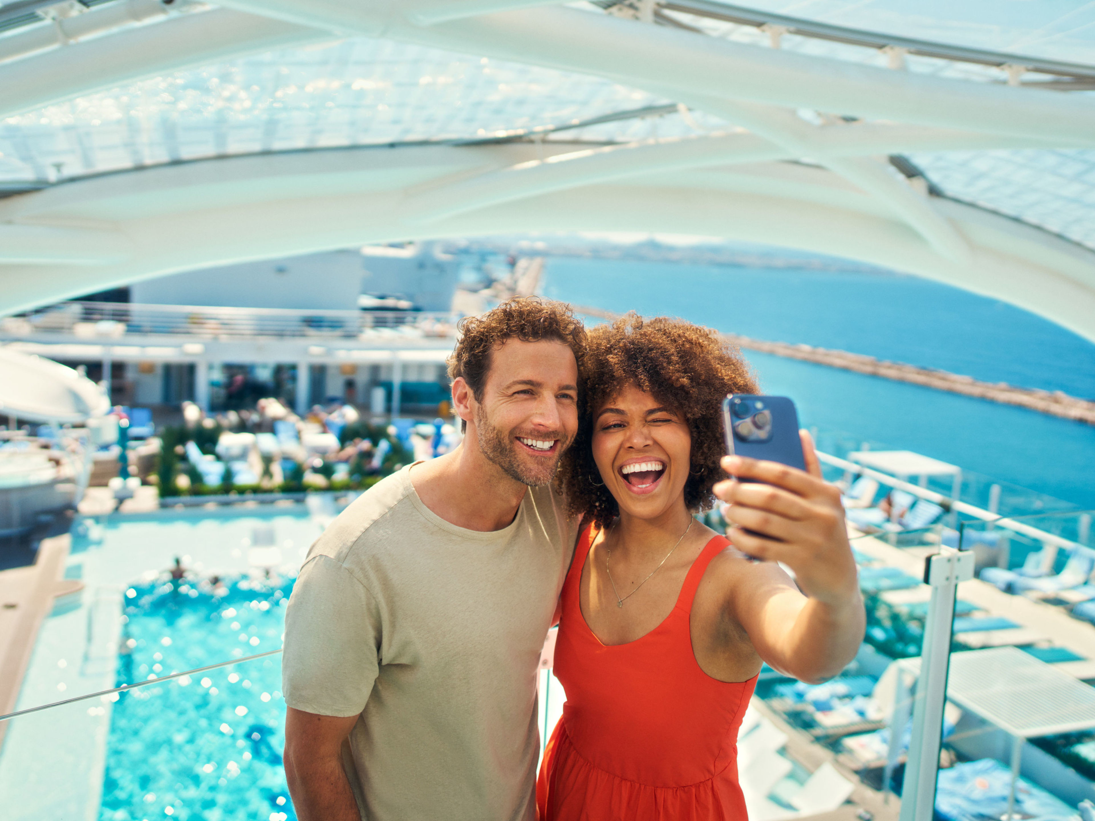 Paar macht Selfie auf Kreuzfahrtschiff der Mein Schiff® Flotte, Pool im Hintergrund. Paar macht Selfie auf Kreuzfahrtschiff der Mein Schiff® Flotte, Pool im Hintergrund.