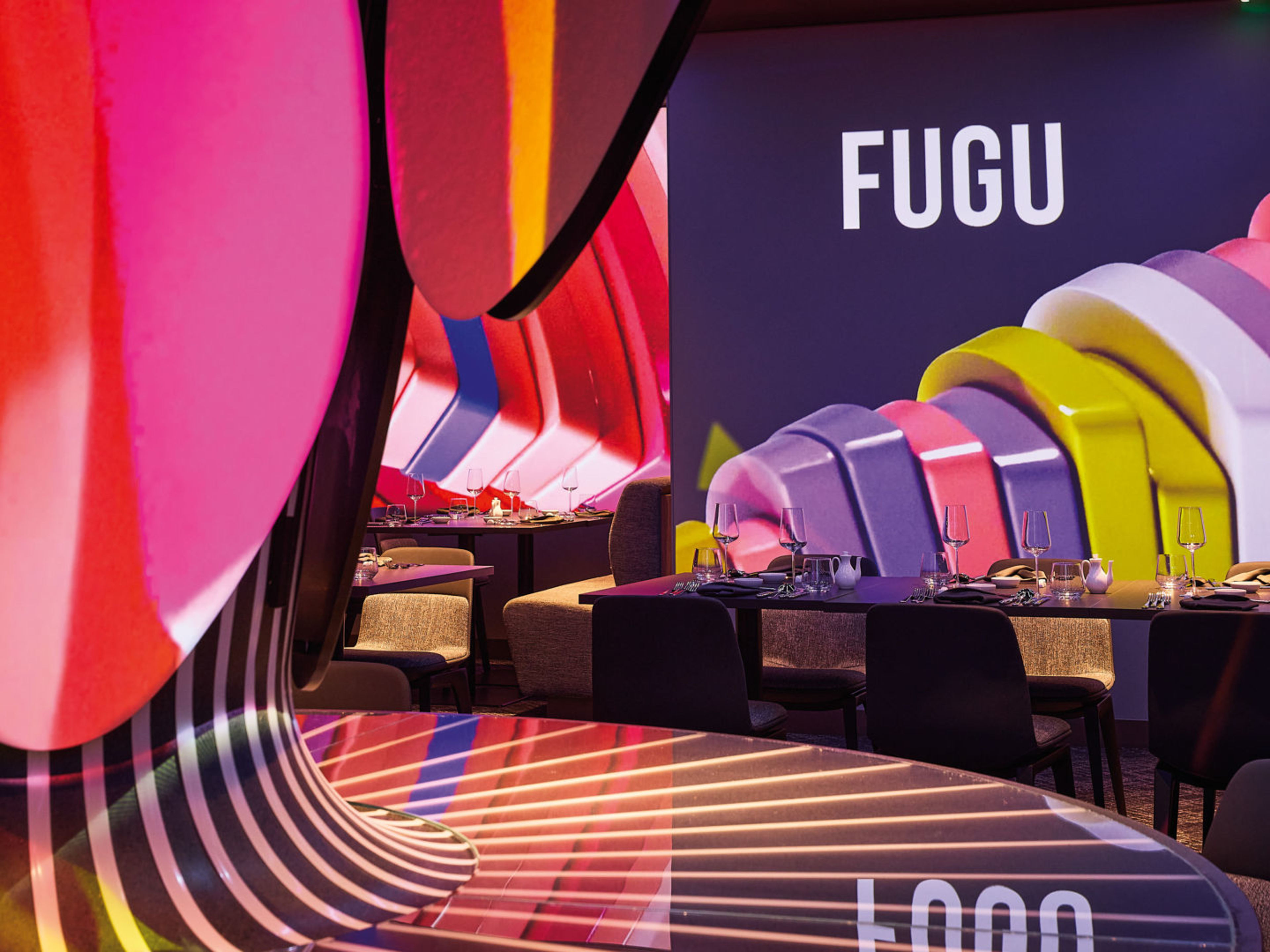 Buntes Restaurantinterieur mit Tischen, Stühlen und FUGU-Schriftzug. Buntes Restaurantinterieur mit Tischen, Stühlen und FUGU-Schriftzug.