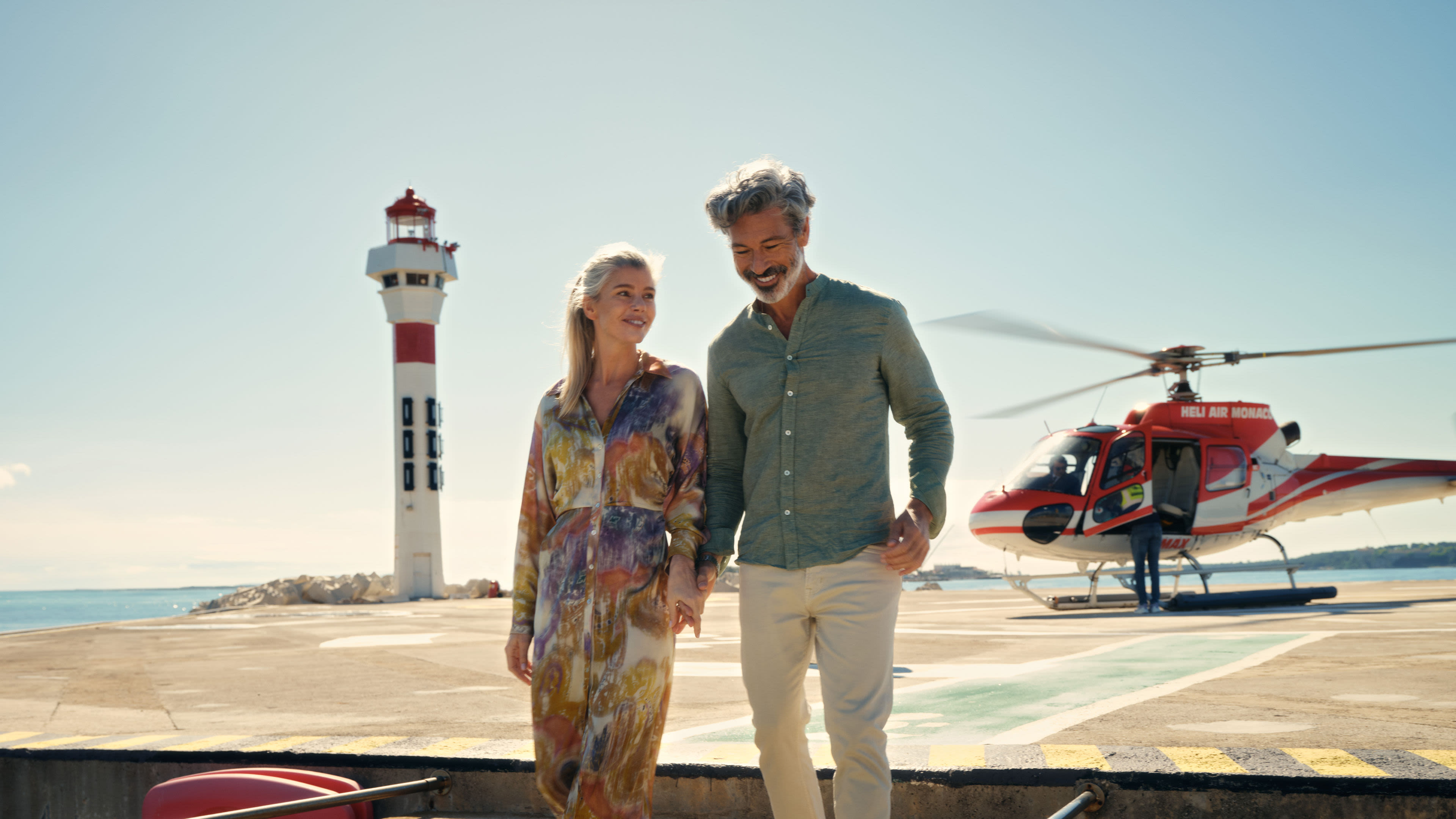 Paar spaziert am Leuchtturm, roter Hubschrauber im Hintergrund. Paar spaziert am Leuchtturm, roter Hubschrauber im Hintergrund.
