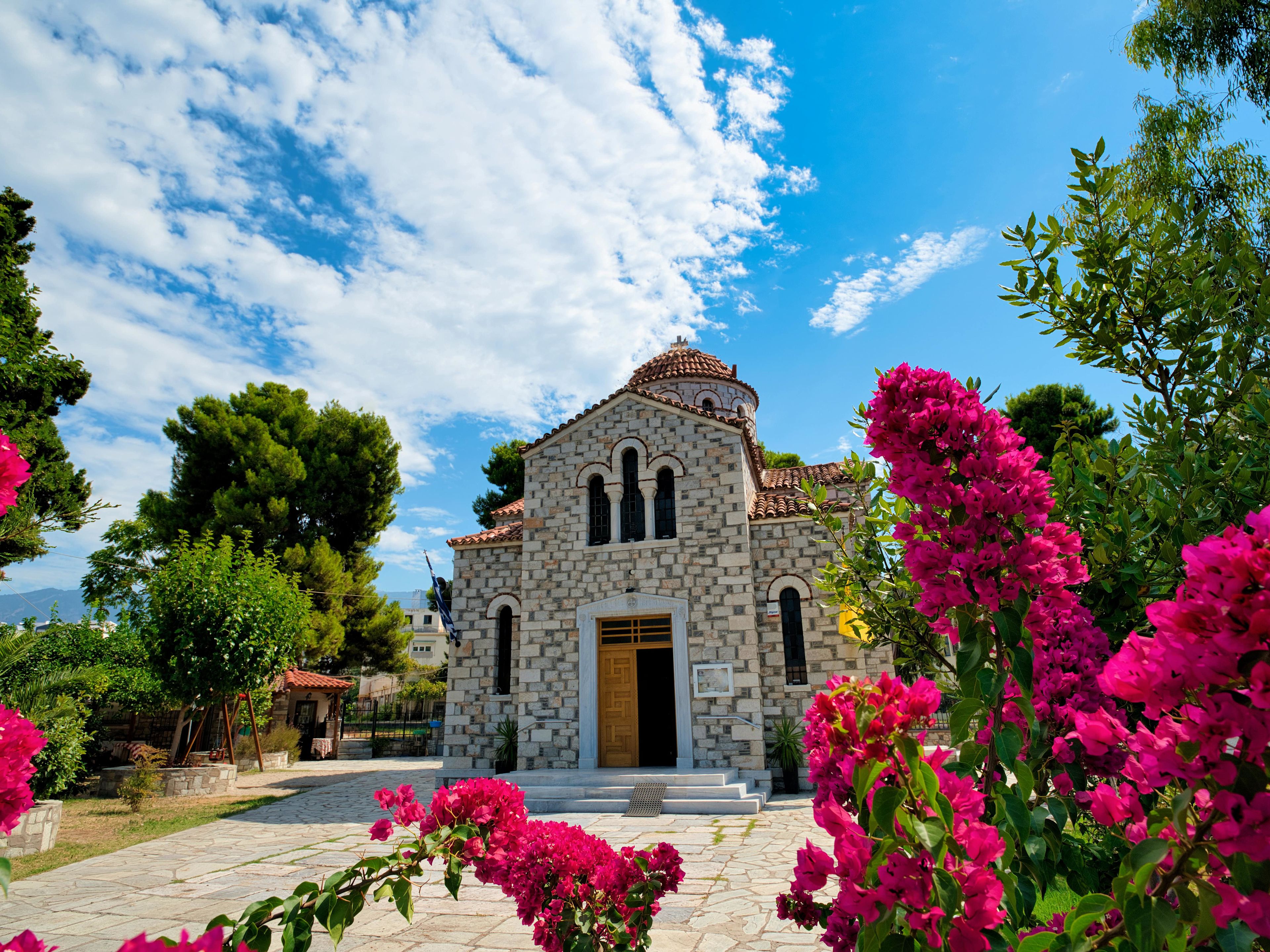 Steinkirche mit rosa Blumen im Vordergrund, blauer Himmel. Steinkirche mit rosa Blumen im Vordergrund, blauer Himmel.
