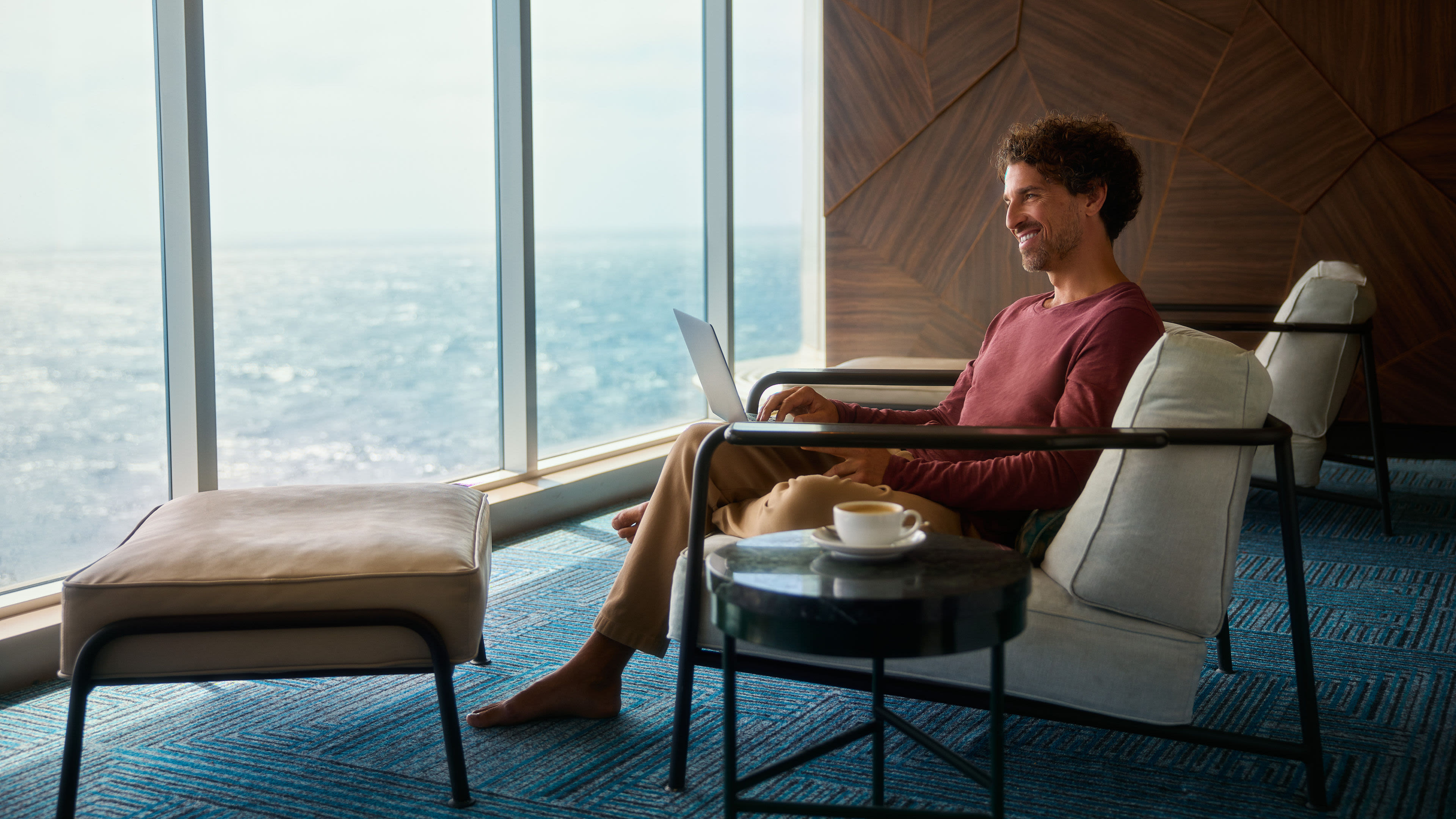Mann entspannt mit Laptop am Fenster, Meerblick. Mann entspannt mit Laptop am Fenster, Meerblick.