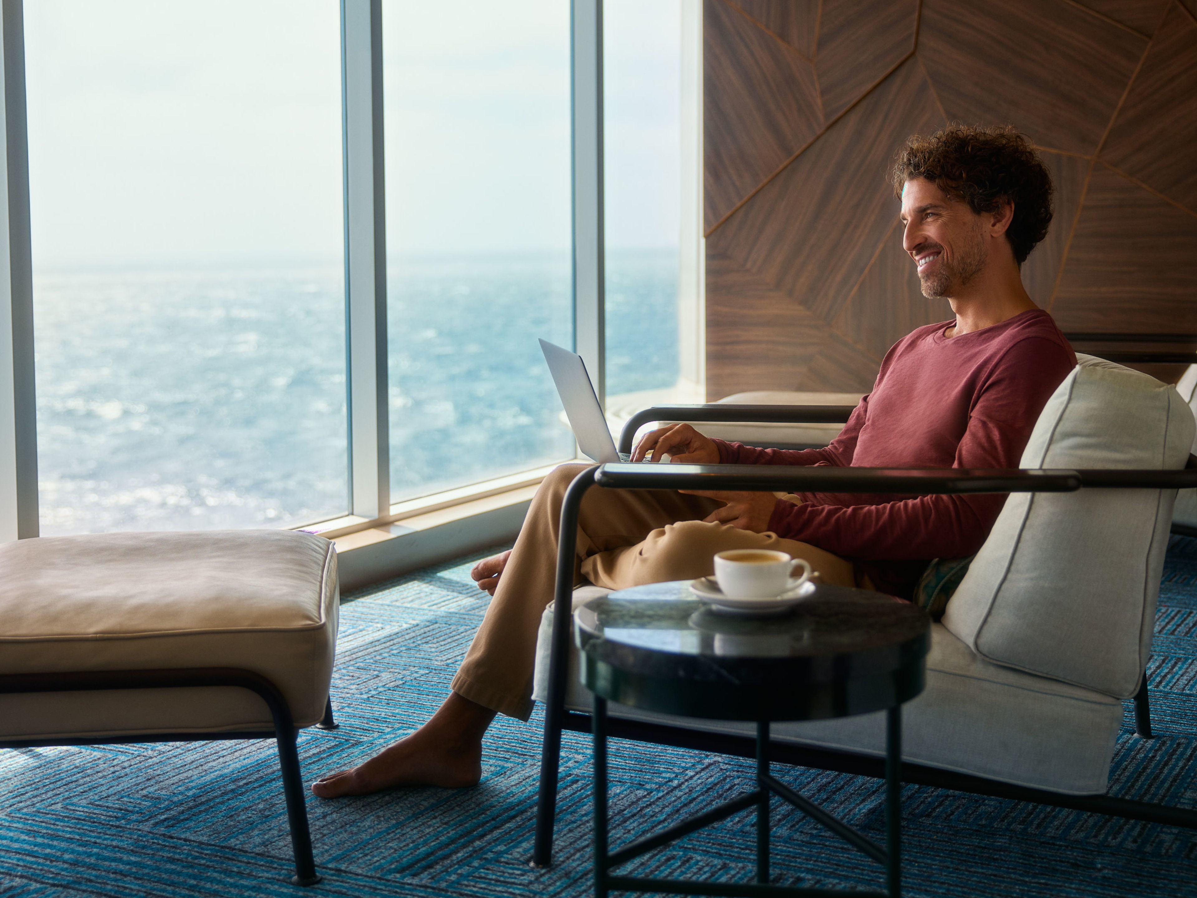 Mann entspannt mit Laptop am Fenster, Meerblick. Mann entspannt mit Laptop am Fenster, Meerblick.