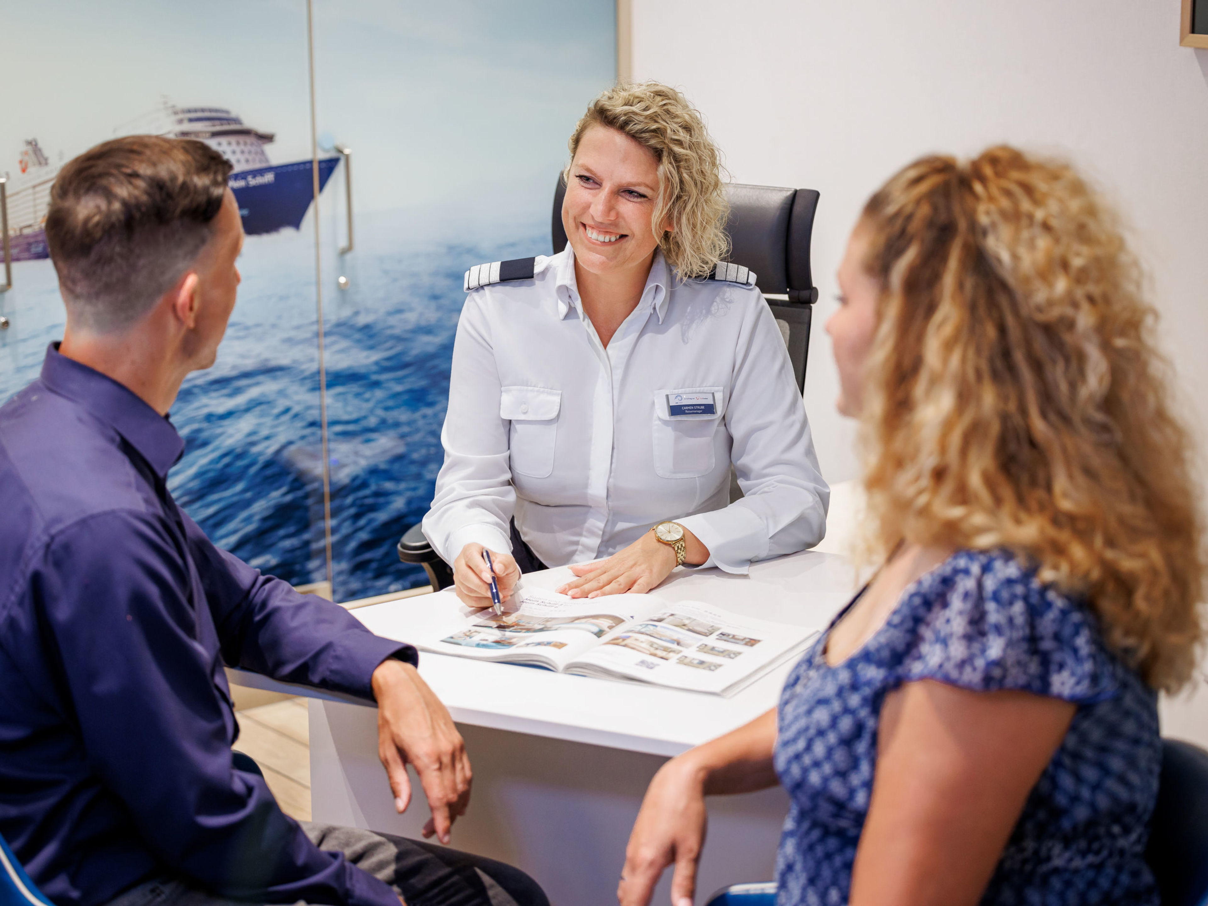 Drei Personen im Beratungsgespräch, Kreuzfahrtschiff der Mein Schiff® Flotte im Hintergrund. Drei Personen im Beratungsgespräch, Kreuzfahrtschiff der Mein Schiff® Flotte im Hintergrund.
