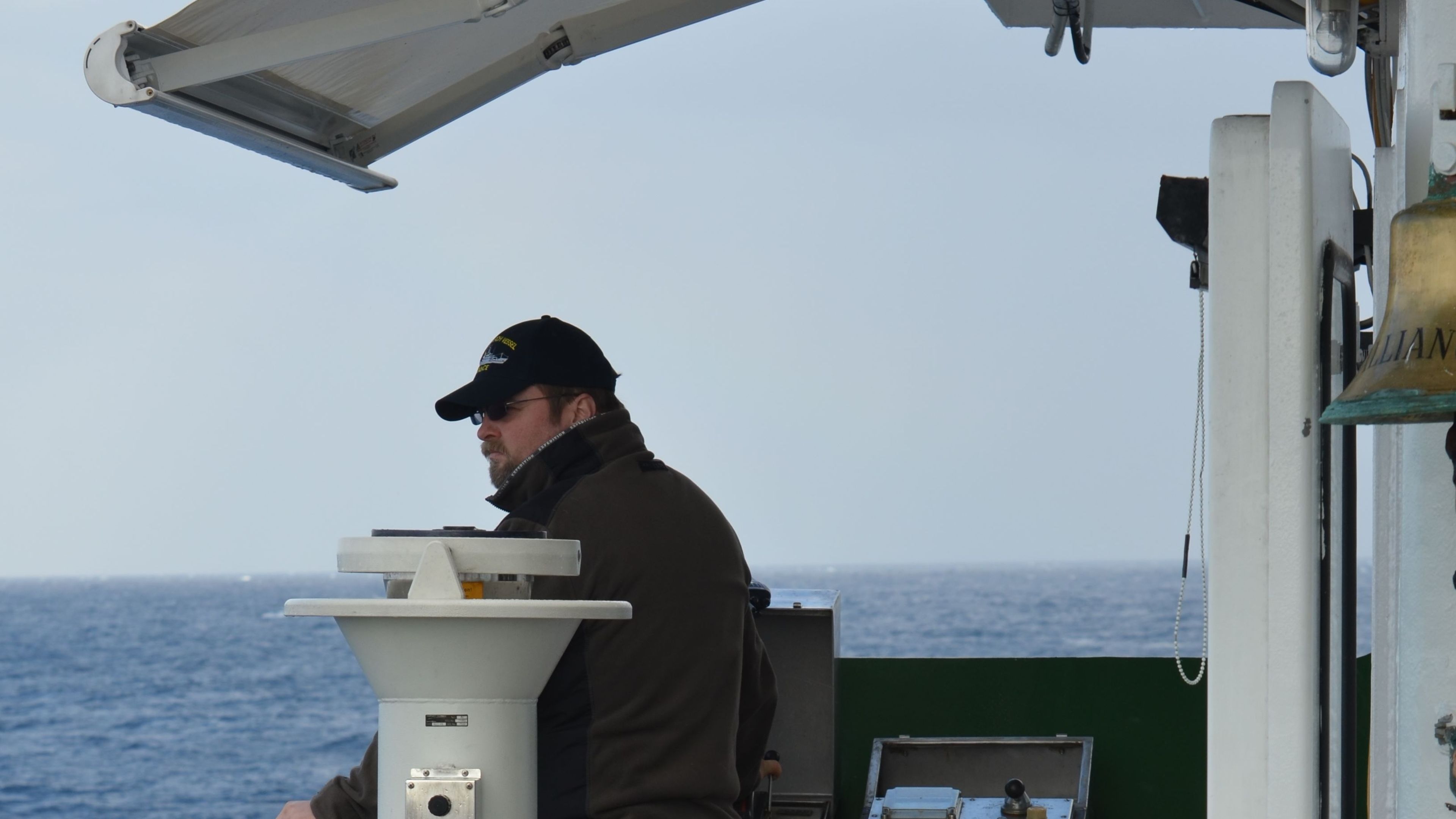 Mann mit Mütze auf Schiff, Meer im Hintergrund. Mann mit Mütze auf Schiff, Meer im Hintergrund.