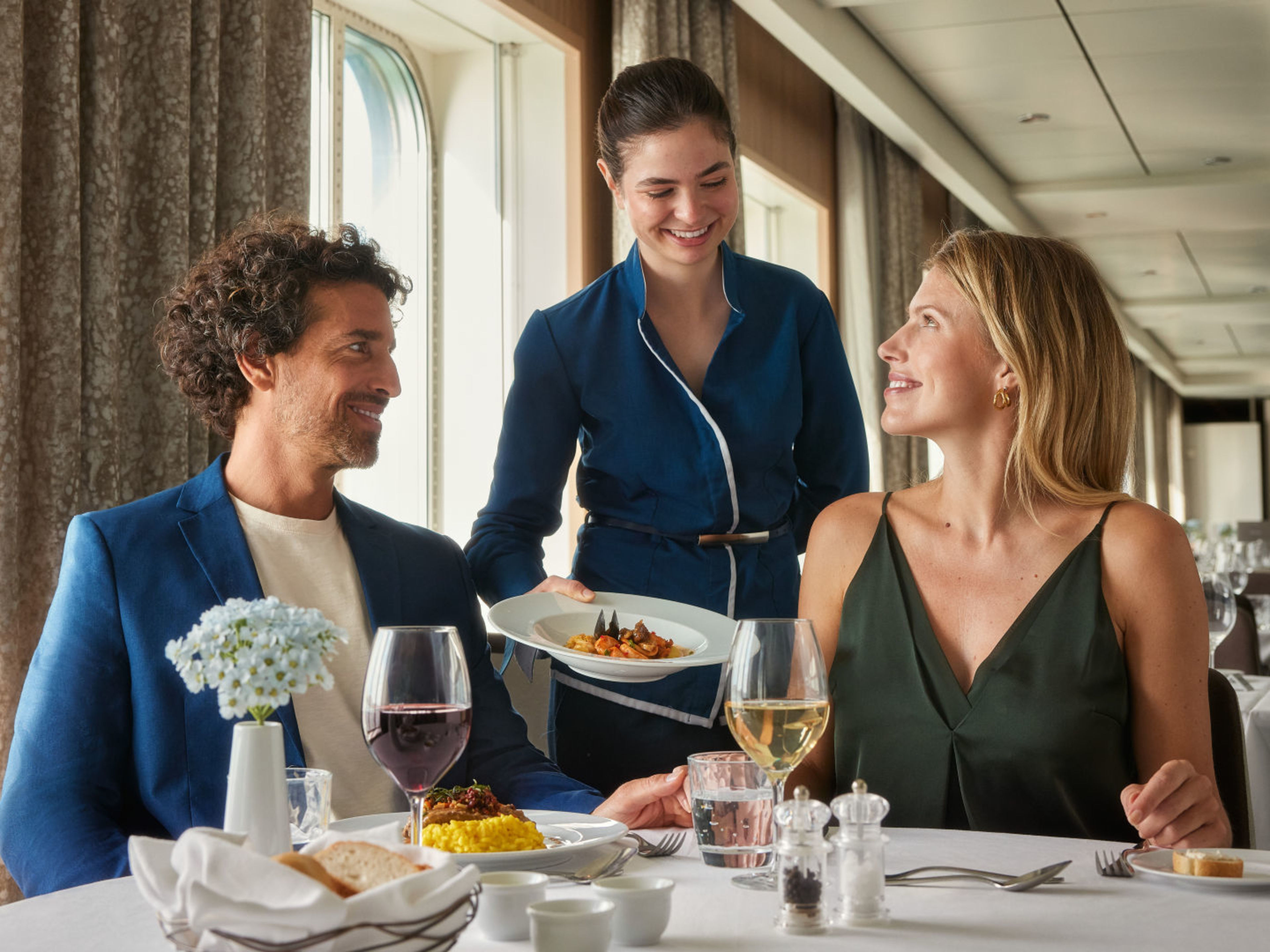 Paar genießt Abendessen, Kellnerin serviert, elegante Atmosphäre, Kreuzfahrtschiff. Paar genießt Abendessen, Kellnerin serviert, elegante Atmosphäre, Kreuzfahrtschiff.