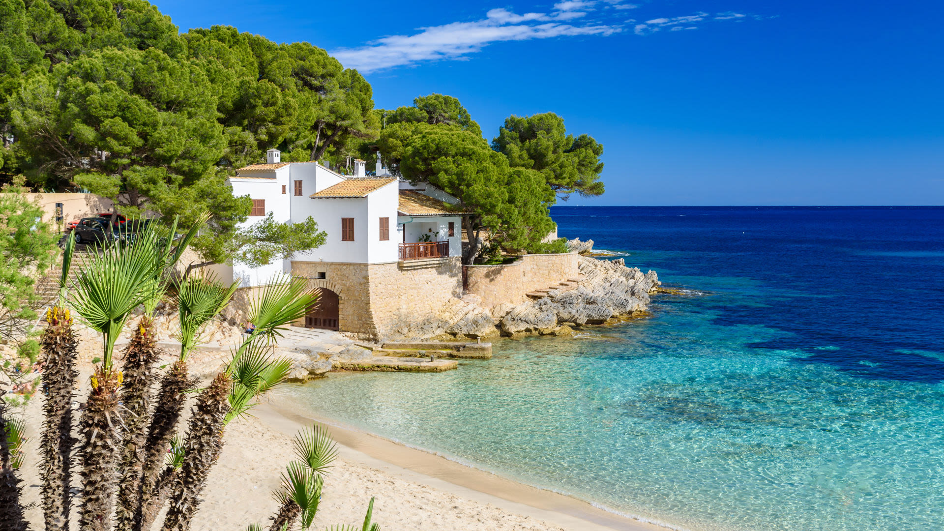 Weißes Haus am Strand von Mallorca, umgeben von Pinien.